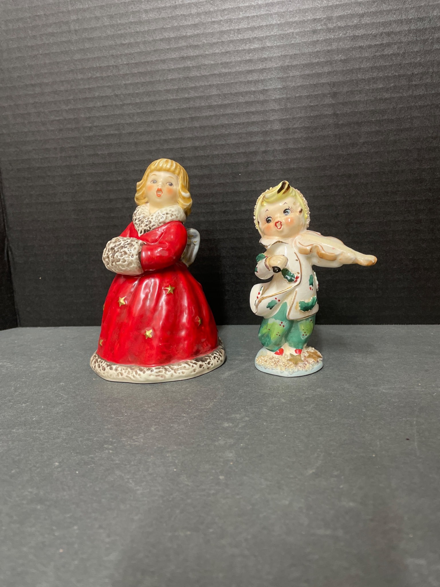 Figurines, Goebel Angel Bell with 1979 Marking and Ceramic Winged Cherub: This lot includes a pair of figurines. One is a Goebel Angel Bell with a 1979 marking, model number 57 192 15, featuring a red dress and silver wings. The other piece is a ceramic winged cherub