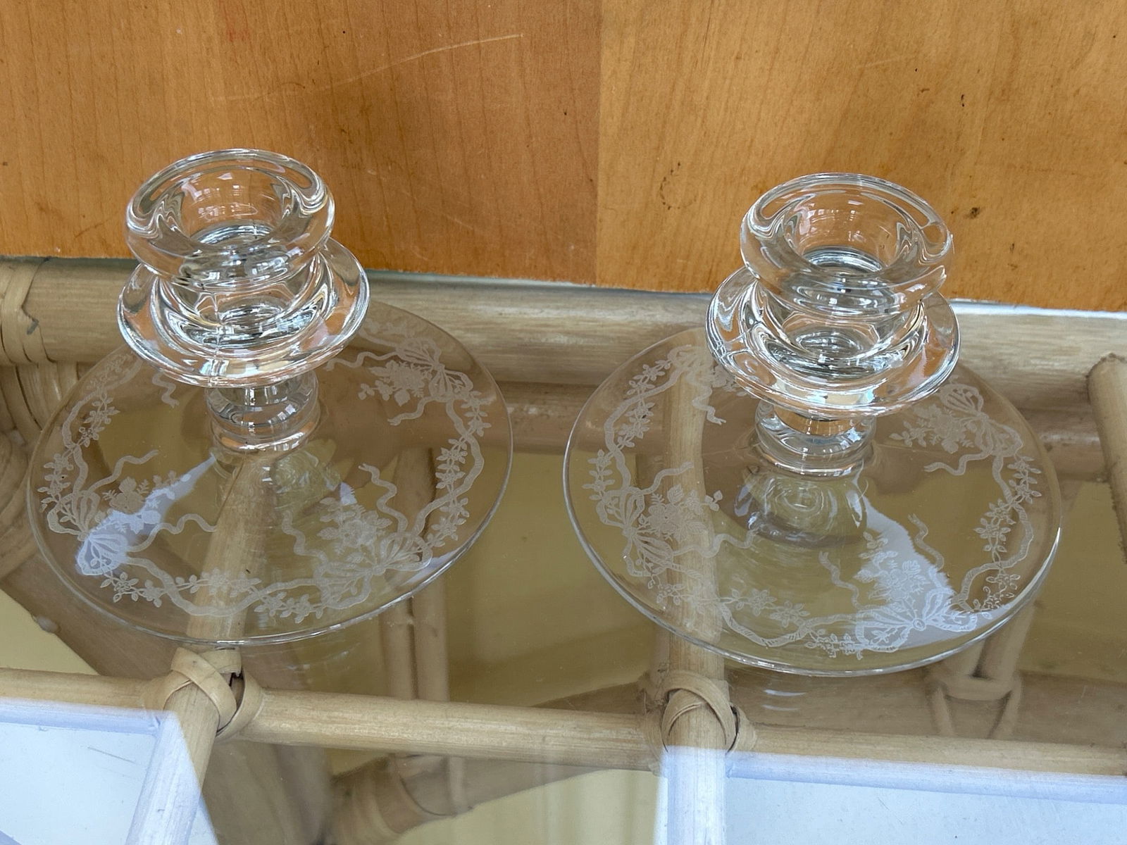 Clear Glass Etched Candle Holders with Floral Design: This is a pair of clear glass candle holders featuring an etched floral design on the base. The items are made of transparent glass, with a flat circular base and a single candlestick holder on top. T