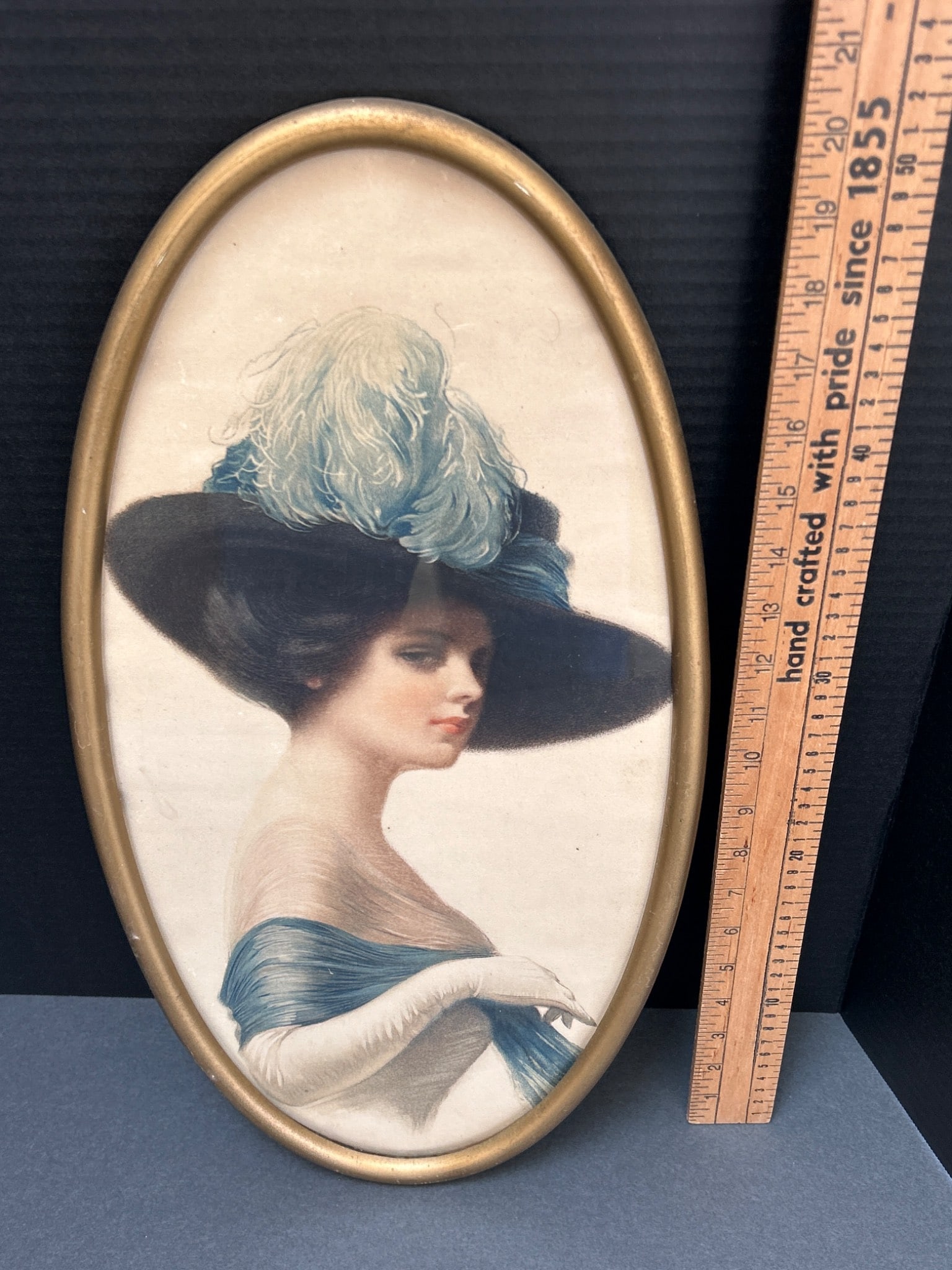 Oval Framed Portrait Print With Killian's Cedar Rapids Label: An oval-shaped framed print featuring a period-style portrait of a woman wearing a feathered hat and wrap. The label on the back indicates 'Killian's Cedar Rapids,' suggesting it was distributed by th