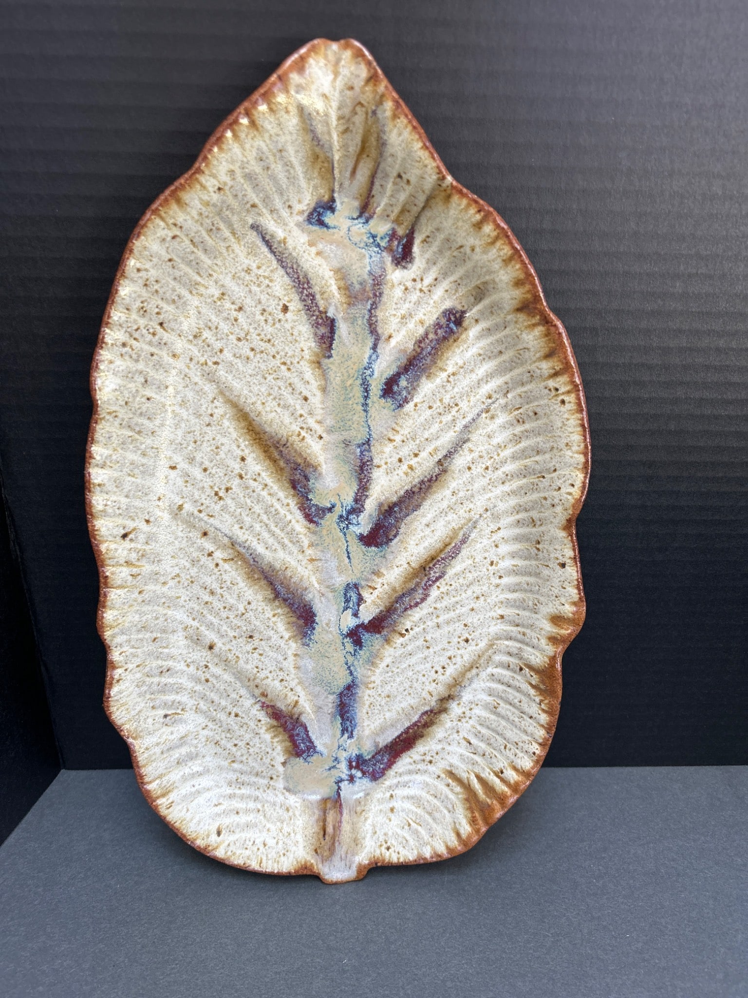 Handcrafted Ceramic Leaf-Shaped Tray with Multicolored Glaze: This ceramic tray is handcrafted in a leaf shape, with dimensions approximately 11 inches in length and 6 inches in width. It features a textured surface and multicolored glaze in earth tones