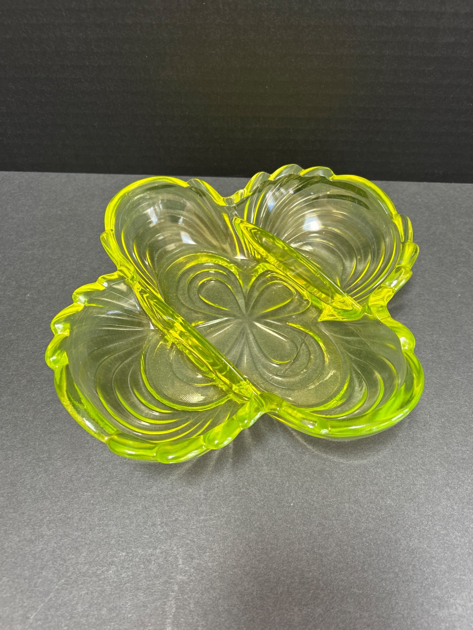 Green Four-Section Glass Dish with Crack, Approximately 9 Inches Wide: A green glass divided dish with four compartments and decorative edging. Measures approximately 9 inches in width as shown. The dish exhibits a visible crack near one of the compartments. Suitable