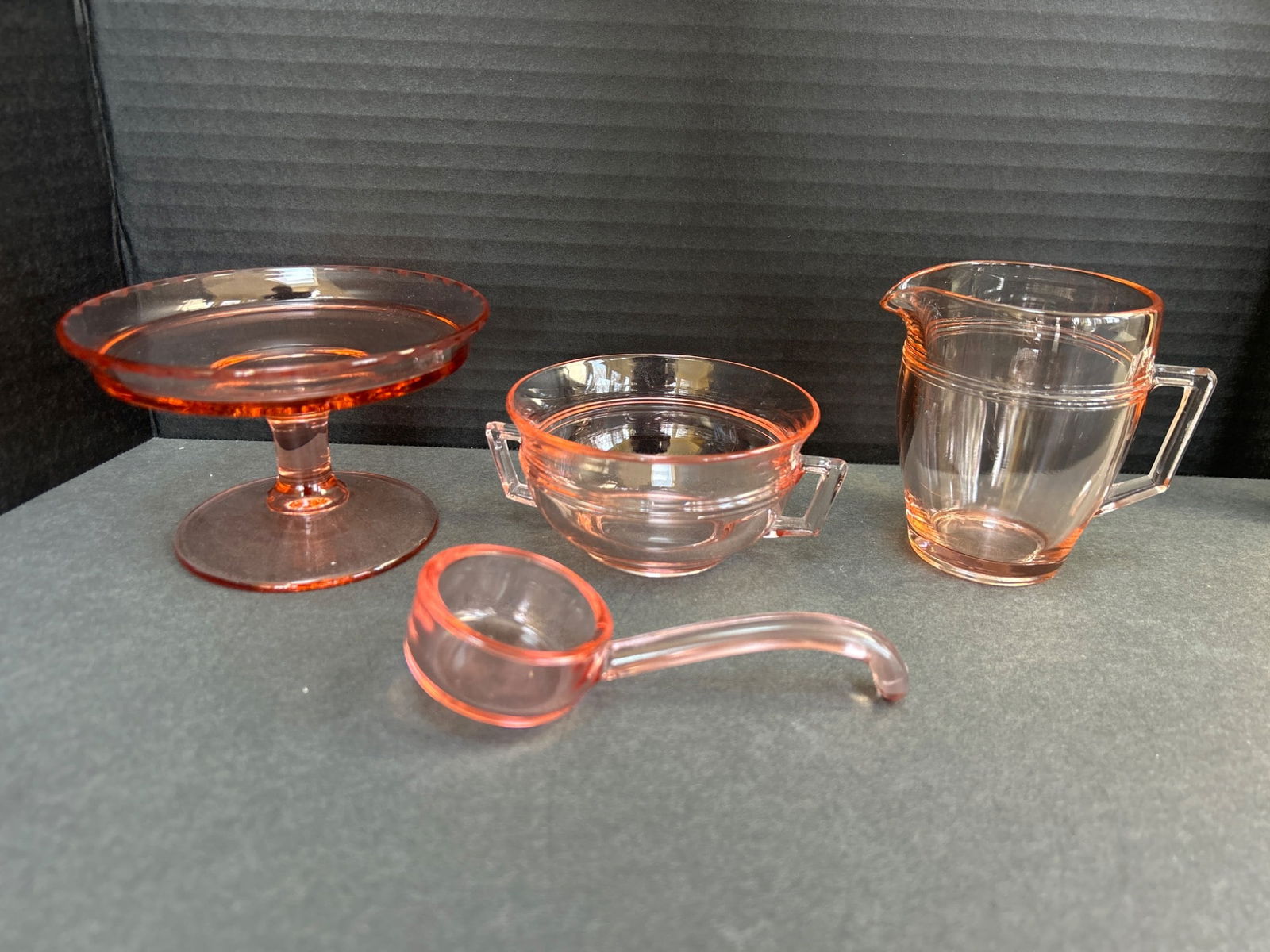 4 Pink Depression Glass Miniatures - Pedestal Dish, Handled Bowl, Pitcher, and Ladle: This is a set of 4 miniature pink Depression glass pieces, including a pedestal dish (approximately 4 inches in diameter), a handled bowl (approximately 2.5 inches in diameter), a small pitcher with a