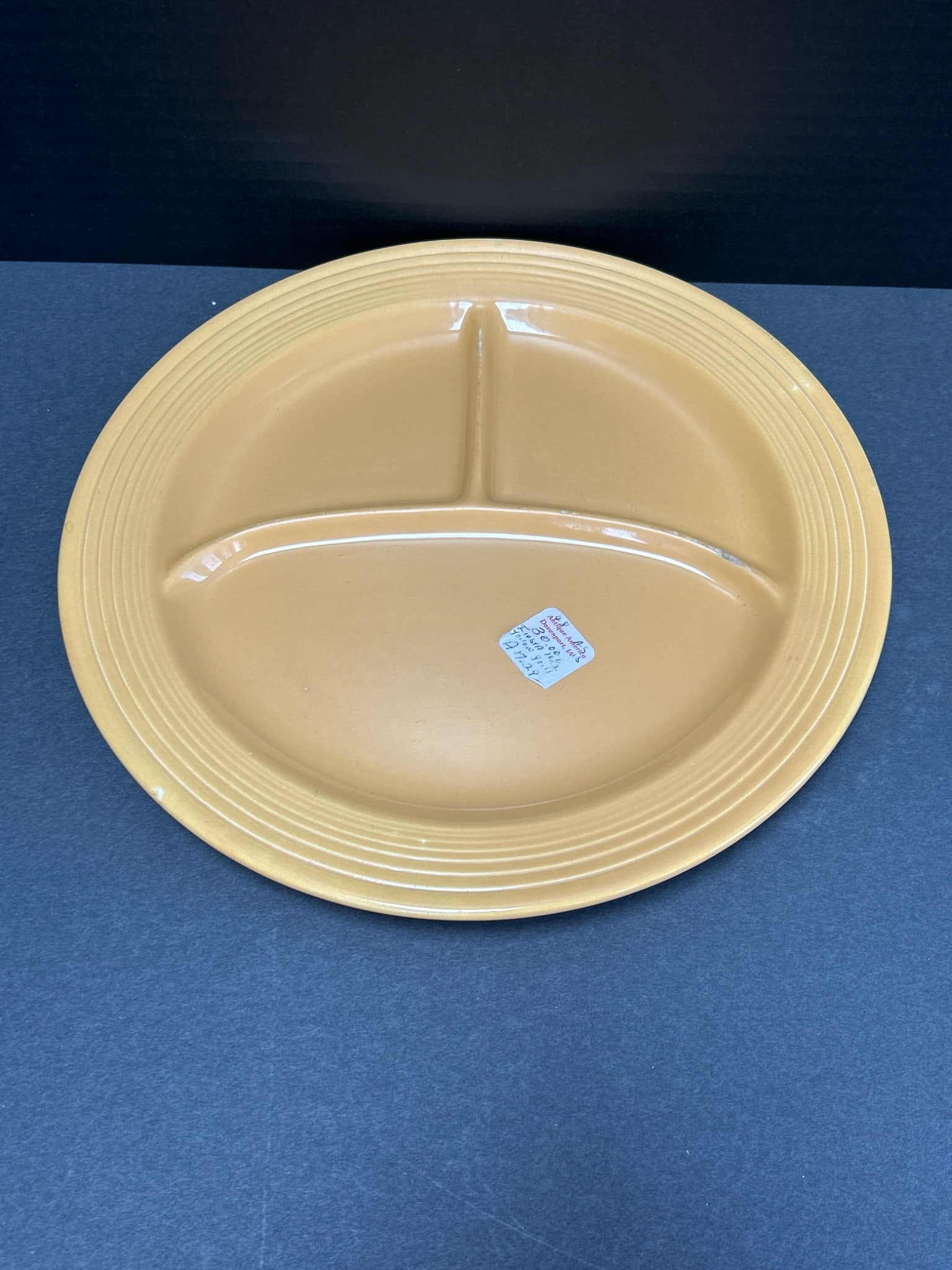 Fiesta Genuine H-L-O USA Yellow Divided Plate with Backstamp: This is a yellow ceramic divided plate manufactured by Fiesta, branded with the Genuine Fiesta H-L-O USA backstamp. The plate measures approximately 10 inches in diameter and features a ribbed edge
