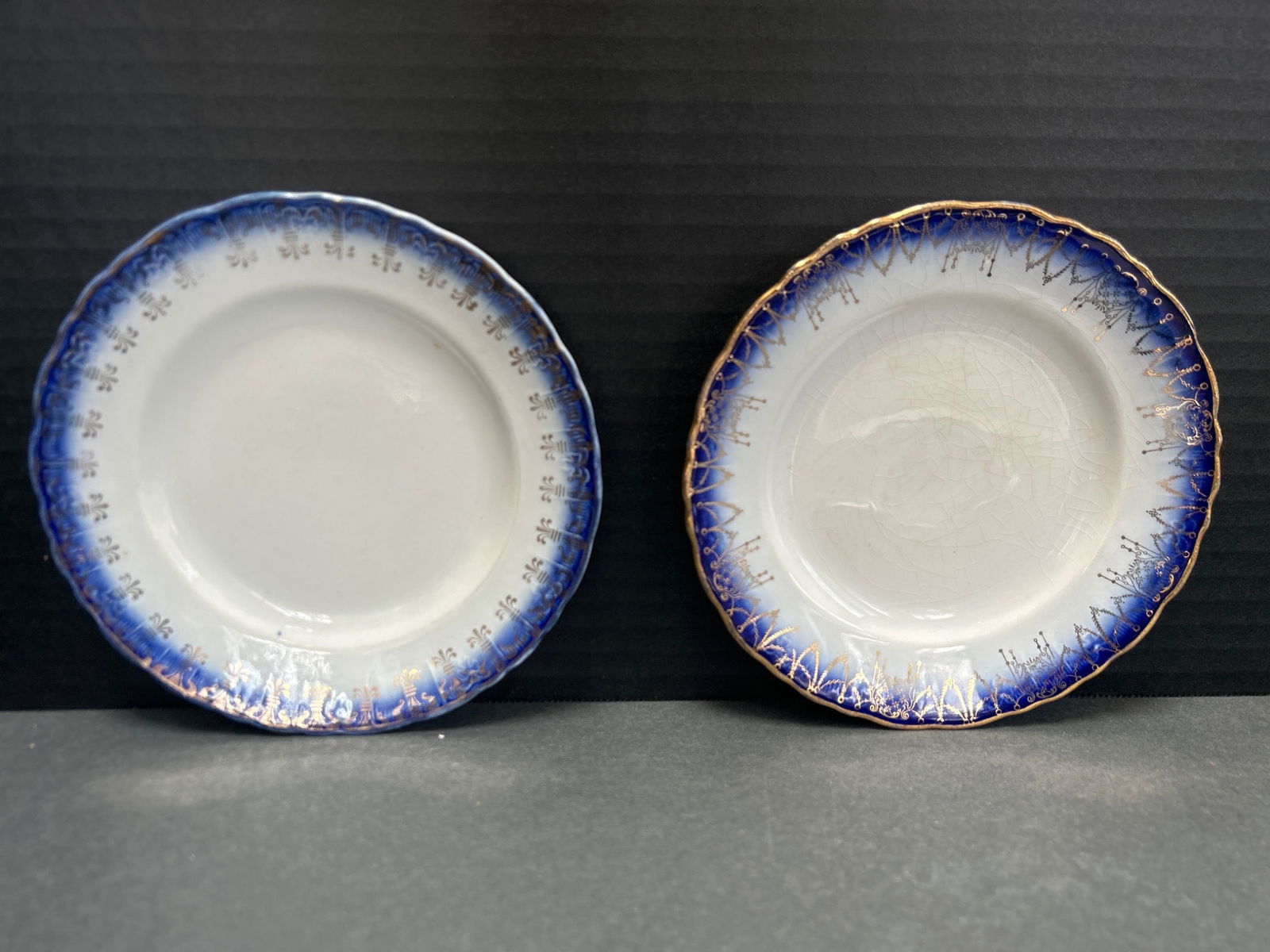 Two Ceramic Plates with Blue and Gold Rim Decoration: Ceramic plates featuring blue gradient borders with gold detailing along the edges. The backside has minor marks and wear, potentially indicative of their age or past use. No manufacturer mark or mode