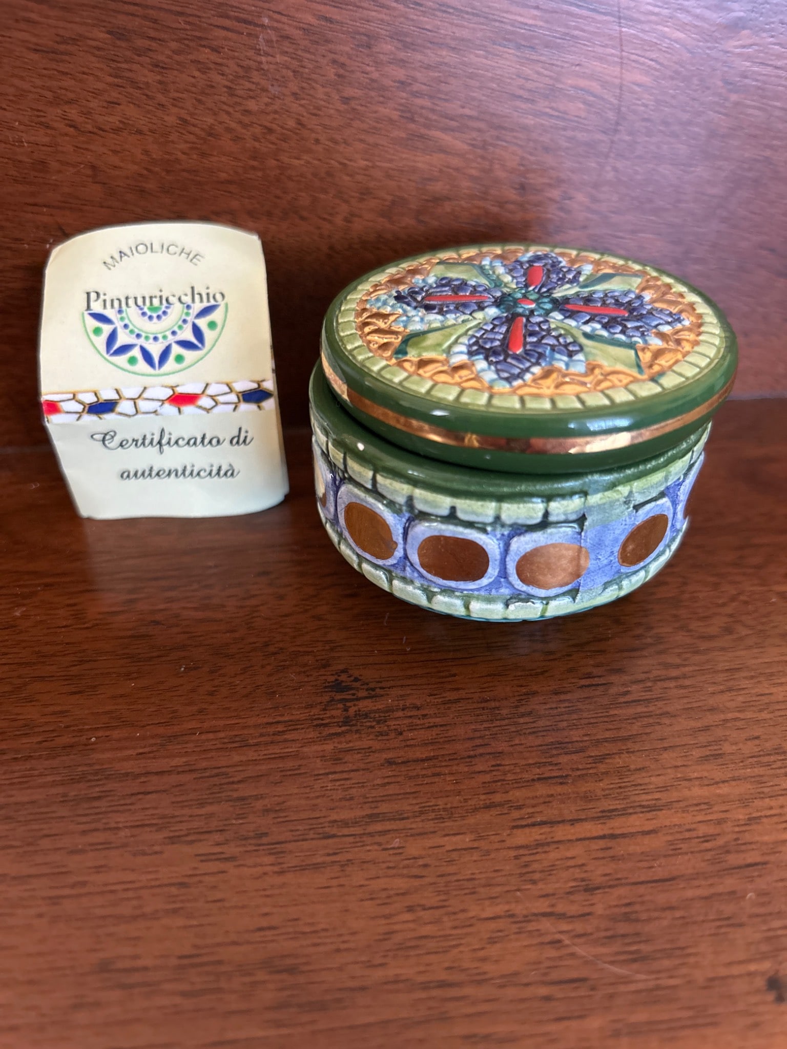 Hand-Painted Italian Maioliche Trinket Box by Pinturicchio, Ravenna Design: This is a hand-painted Italian ceramic trinket box marked 'Pinturicchio' with a Ravenna design. It features a circular shape, intricate decorative patterns, and gold accents. The box includes a