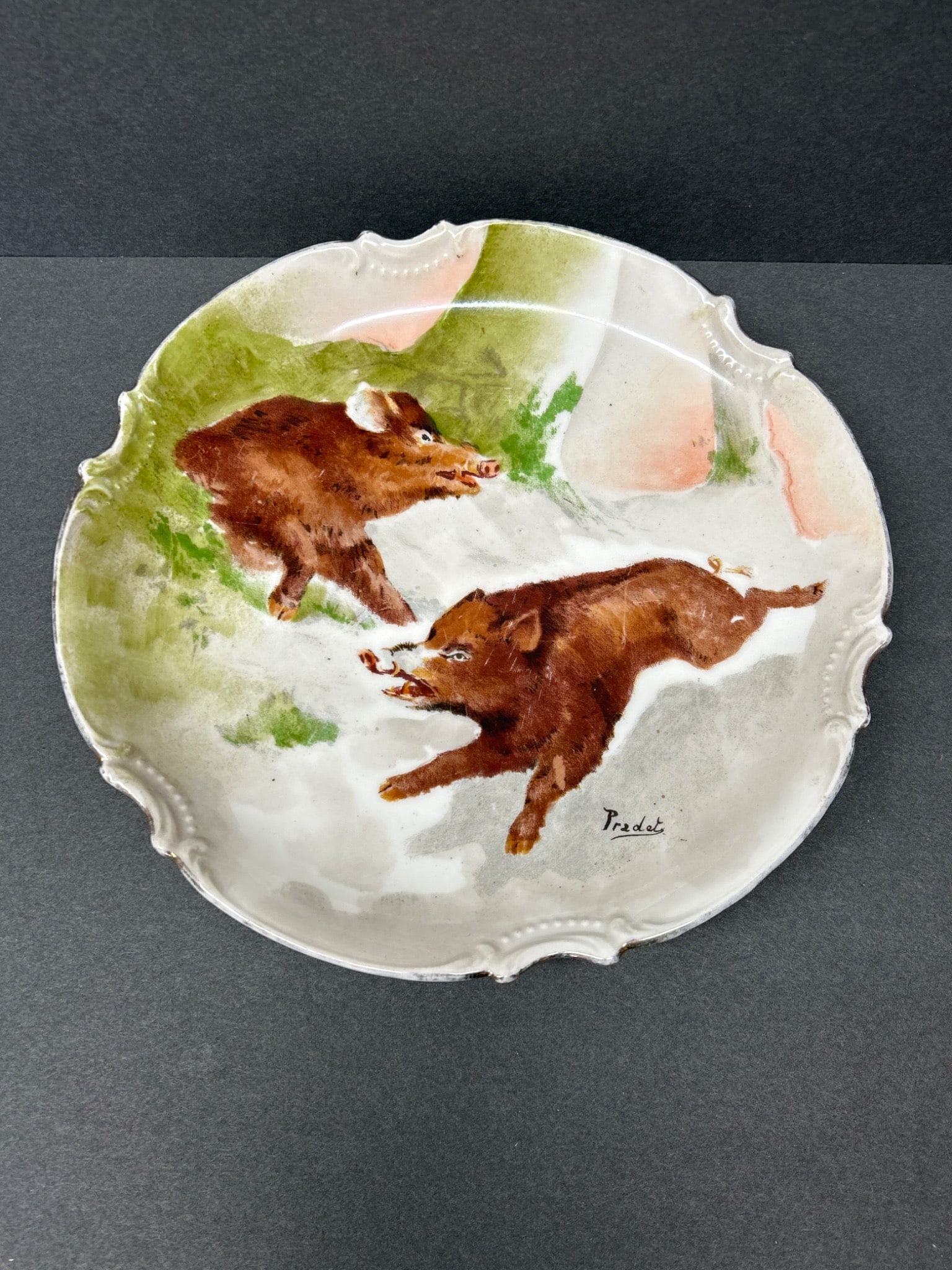 Limoges France C. Ahrenfeldt Handpainted Plate with Wild Boar Design: A Limoges porcelain plate featuring a hand-painted depiction of wild boars, signed by the artist 'Predet.' The plate has scalloped edges and measures approximately 8.5 inches in diameter. Marked on