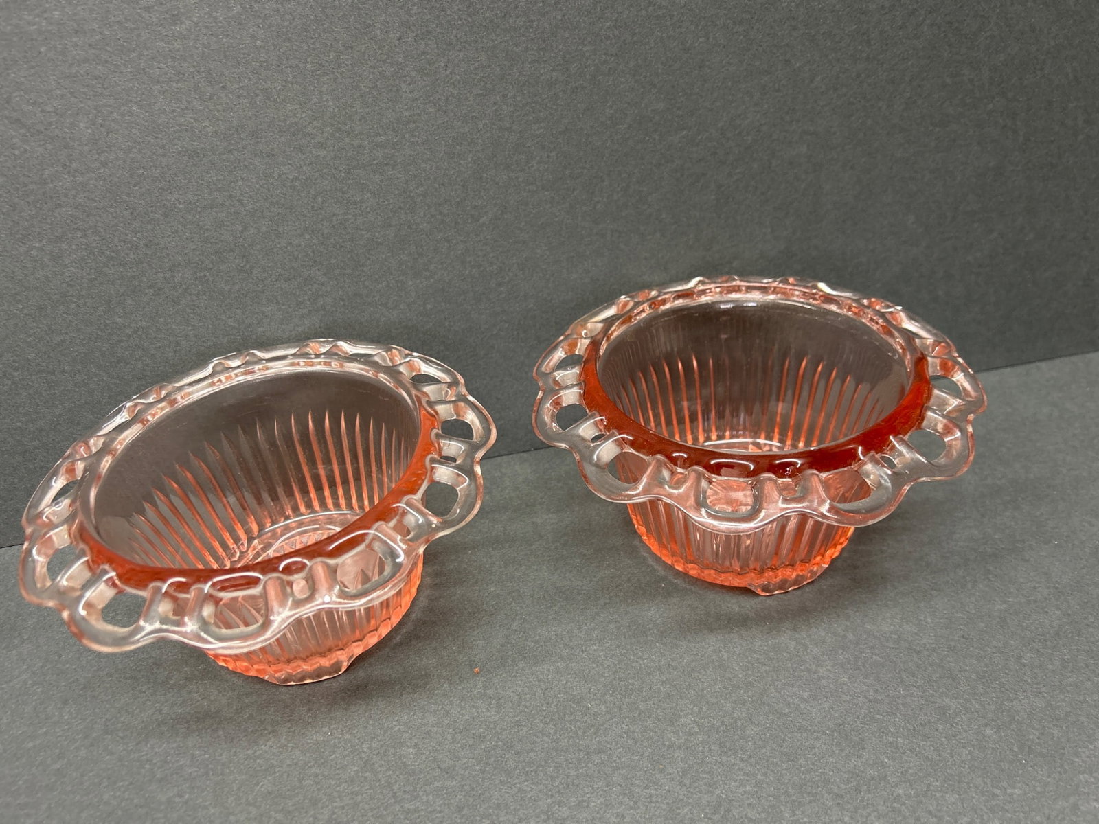 Pink Glass Bowls with Ribbed Body and Scalloped Rim: This lot includes two pink glass bowls with ribbed bodies and decorative scalloped rims. The bowls feature a starburst pattern on the bottom and measure approximately 5.5 inches in diameter across