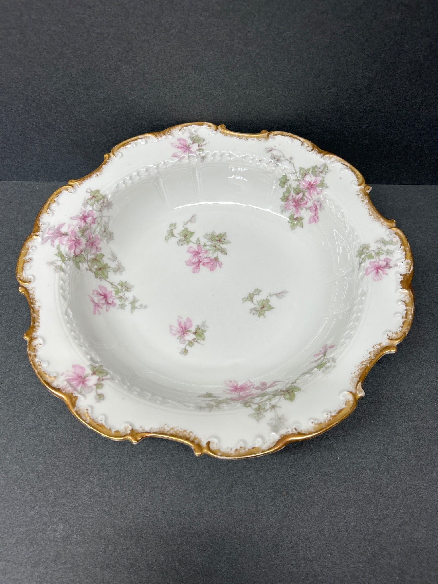 GDA Limoges Scalloped Porcelain Bowl with Floral Design, Approx. 9 Inches: This is a scalloped porcelain bowl produced by GDA Limoges. It features pink floral motifs and gold-accented edges. The bowl measures approximately 9 inches in diameter and has dual backstamps: one