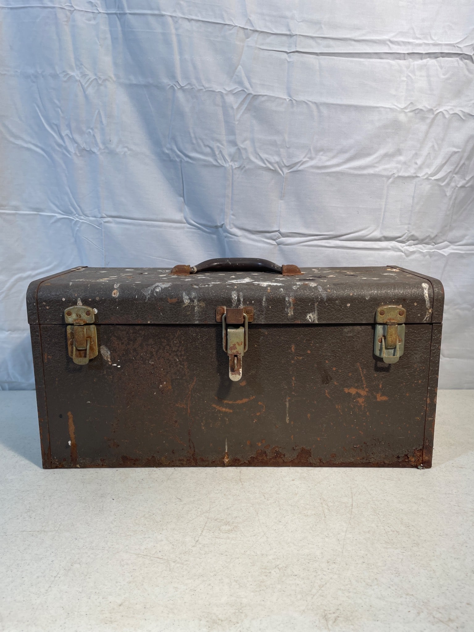 Metal Toolbox With Assorted Hand Tools and Accessories: A metal toolbox containing assorted tools, including pliers, screwdrivers, hammers, a saw blade, and other hand tools. Includes a top interior tray with storage space beneath. Toolbox features a