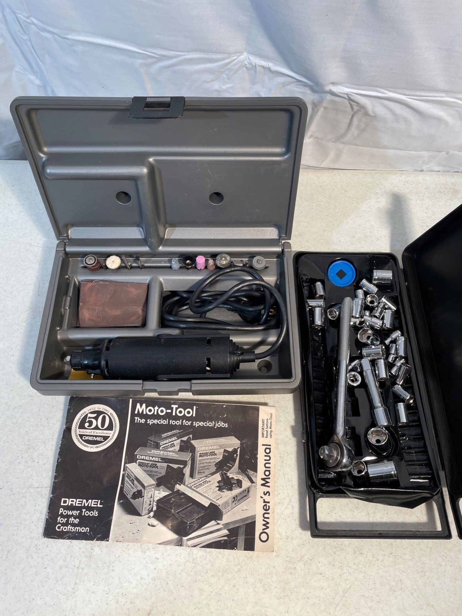Dremel Moto-Tool Power Tool with Accessories and Socket Wrench Set: This lot includes a Dremel Moto-Tool power tool with its original case, accessories such as grinding and polishing tips, a user manual, and a set of socket wrench tools. The Dremel tool appears corded