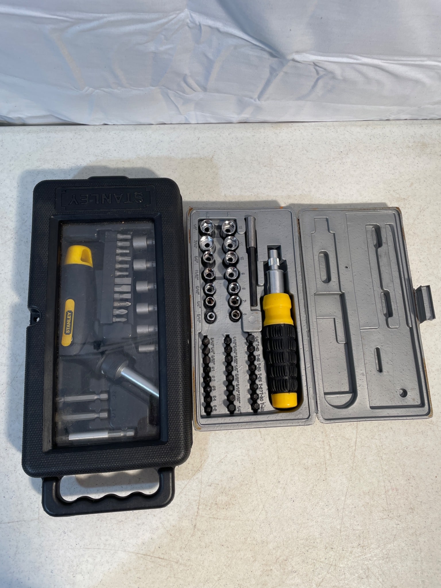 Stanley Multi-Bit Screwdriver and Socket Tool Sets with Cases: This lot includes two Stanley tool sets: a multi-bit screwdriver with a ratchet mechanism and interchangeable bits, and a socket and screwdriver bit set with holder and case. Both sets feature storage