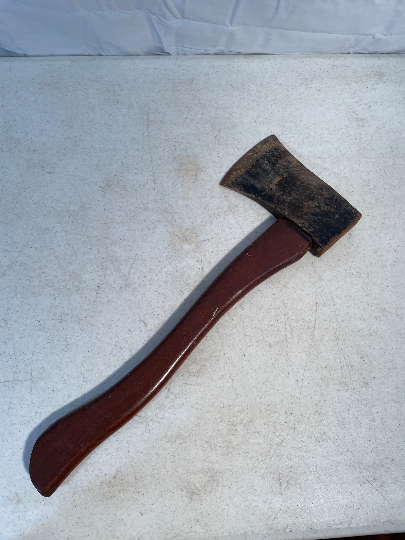 Wood-Handled Hatchet with Metal Head and Secured Bolt Attachment: This hatchet features a curved wooden handle with a metal head. The head appears secured to the handle with a bolt attachment, ensuring stability. The blade shows signs of use with visible wear. Dimen