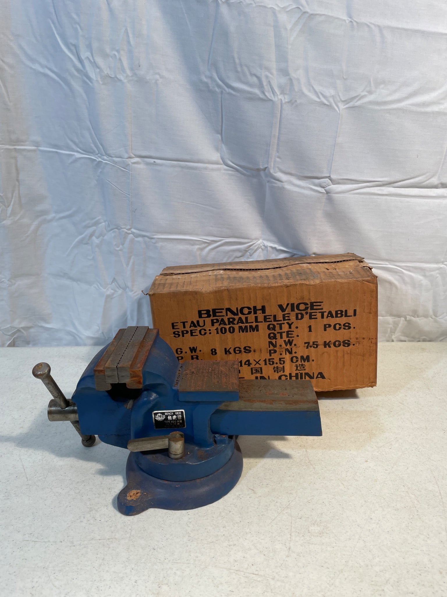 Bench Vise, Model 100mm, Rotatable, Made in China: Bench vise with 100mm jaw width, rotatable base for versatile applications. Original box included, marked with specifications. Manufactured in China. Appears unused or minimally used, showing minor