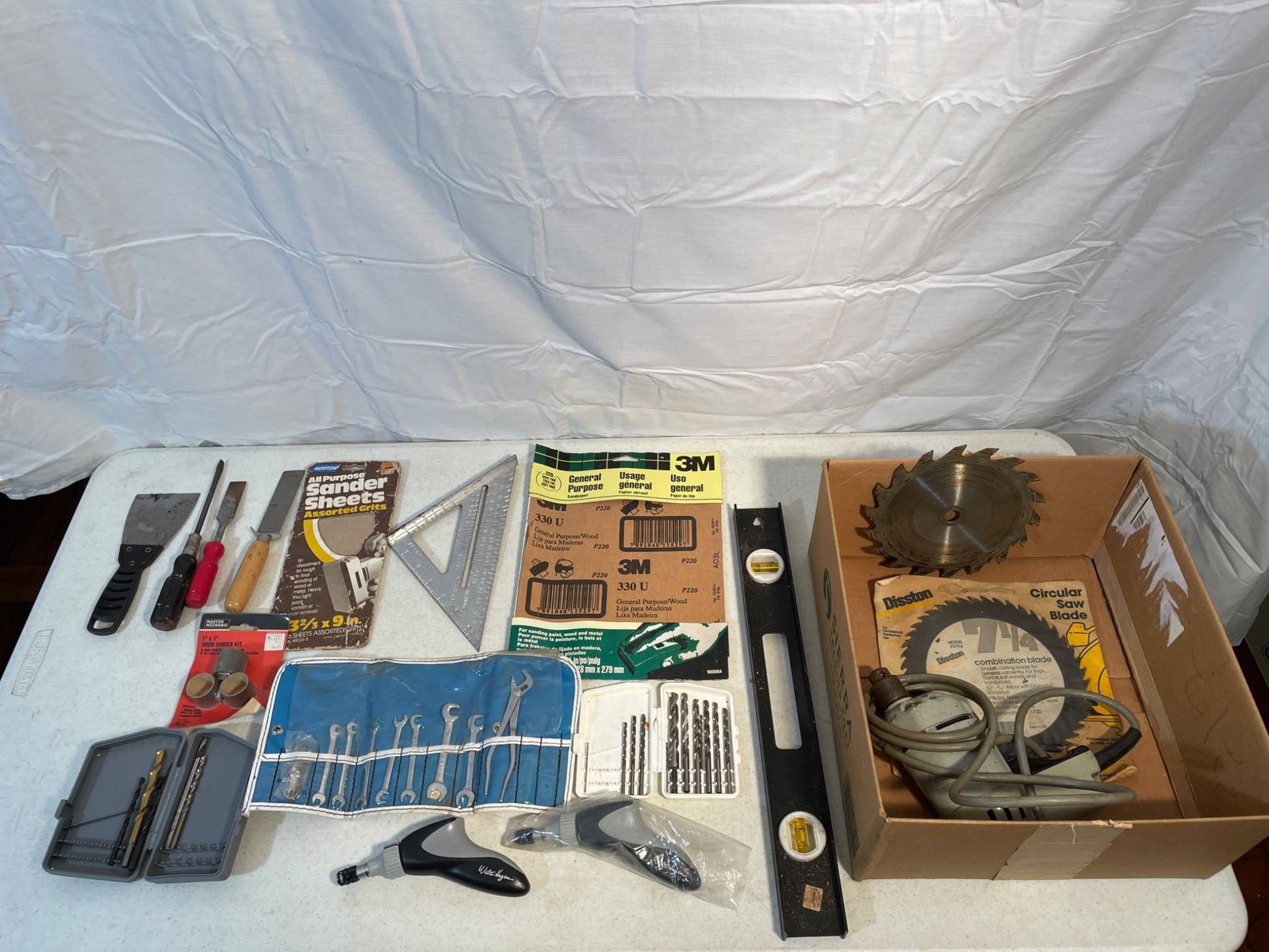 Tools and Circular Saw with Blades: This lot features a variety of hand tools and accessories, including screwdrivers, a tool kit, circular saw blades (notably a Disston combination blade), and an electric circular saw. Additional items