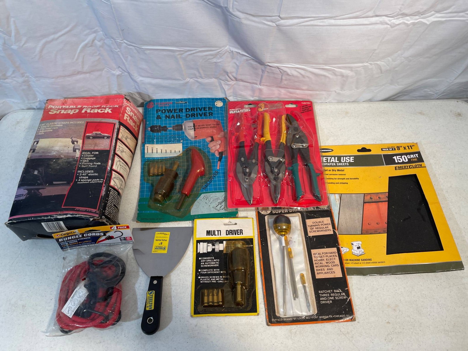 Hardware Tools and Accessories Including Rack, Drivers, and Utility Kit: This lot includes various hardware items such as a portable roof gear snap rack, power driver, screwdrivers, metal snips, a scraper, multi-driver tool, and an 8 x 11 in metal-use sandpaper sheets kit.
