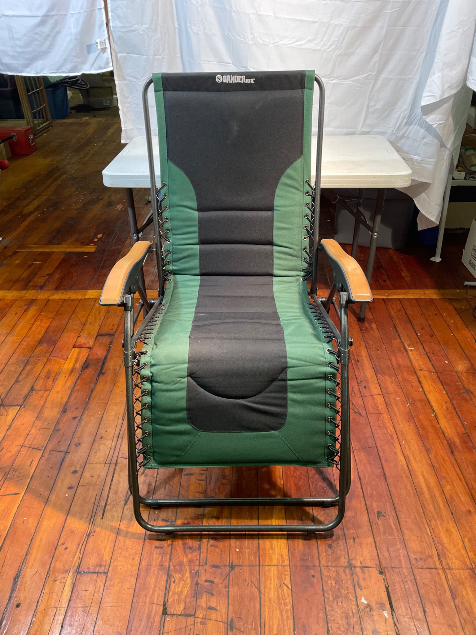 Gander Arctic Reclining Lounge Chair With Padded Seat and Steel Frame: This is a Gander Arctic Reclining Lounge Chair designed with a padded seat and backrest, green and black mesh fabric, and a robust steel frame. It features wooden armrests and a folding mechanism for 