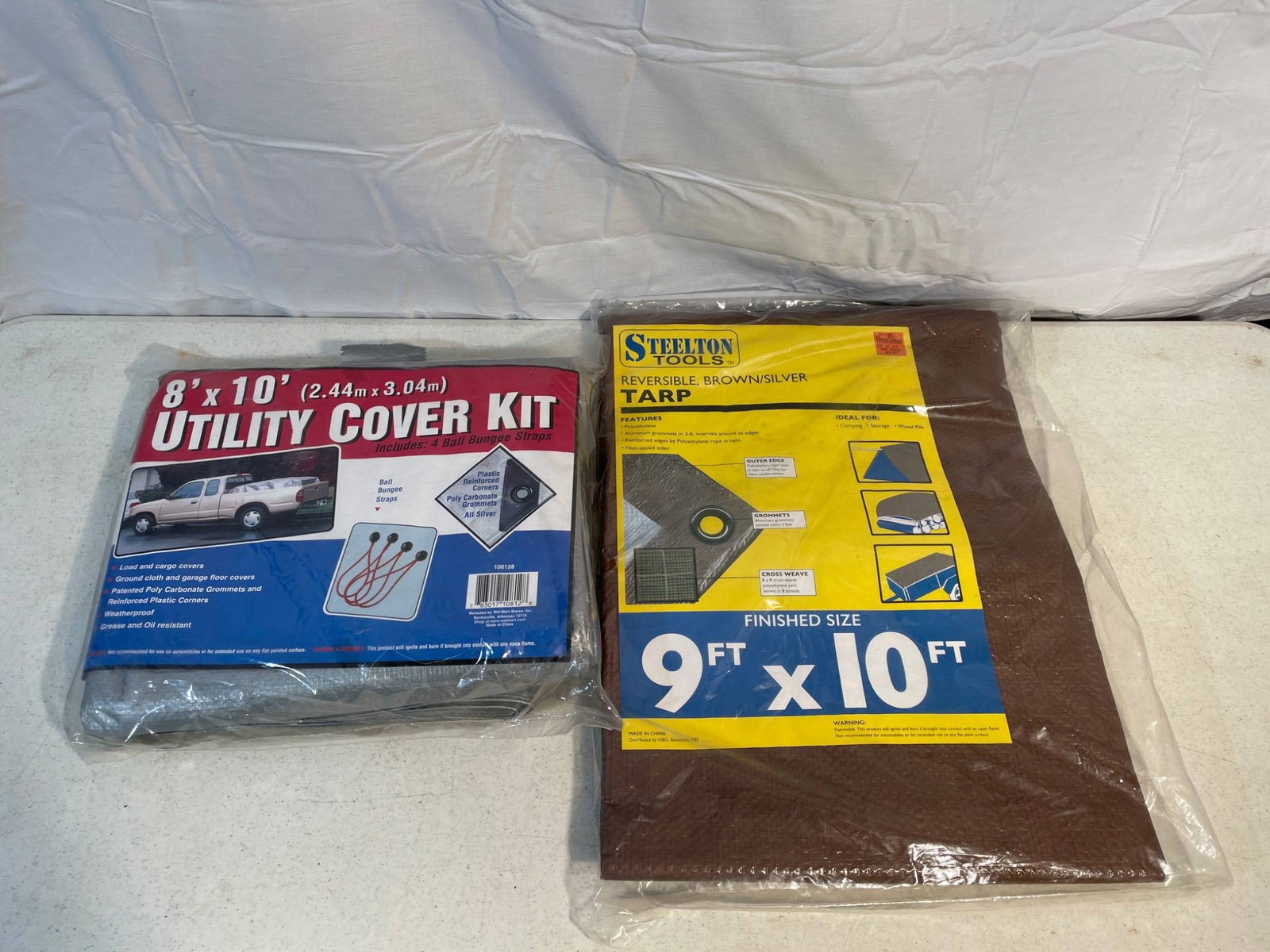 8'x10' Utility Cover Kit and 9'x10' Brown Tarp Set: This lot contains two items: an 8'x10' Utility Cover Kit with reinforced grommets and a 9'x10' brown tarp, also featuring reinforced grommets for secure fastening. Both are packaged and appear to be