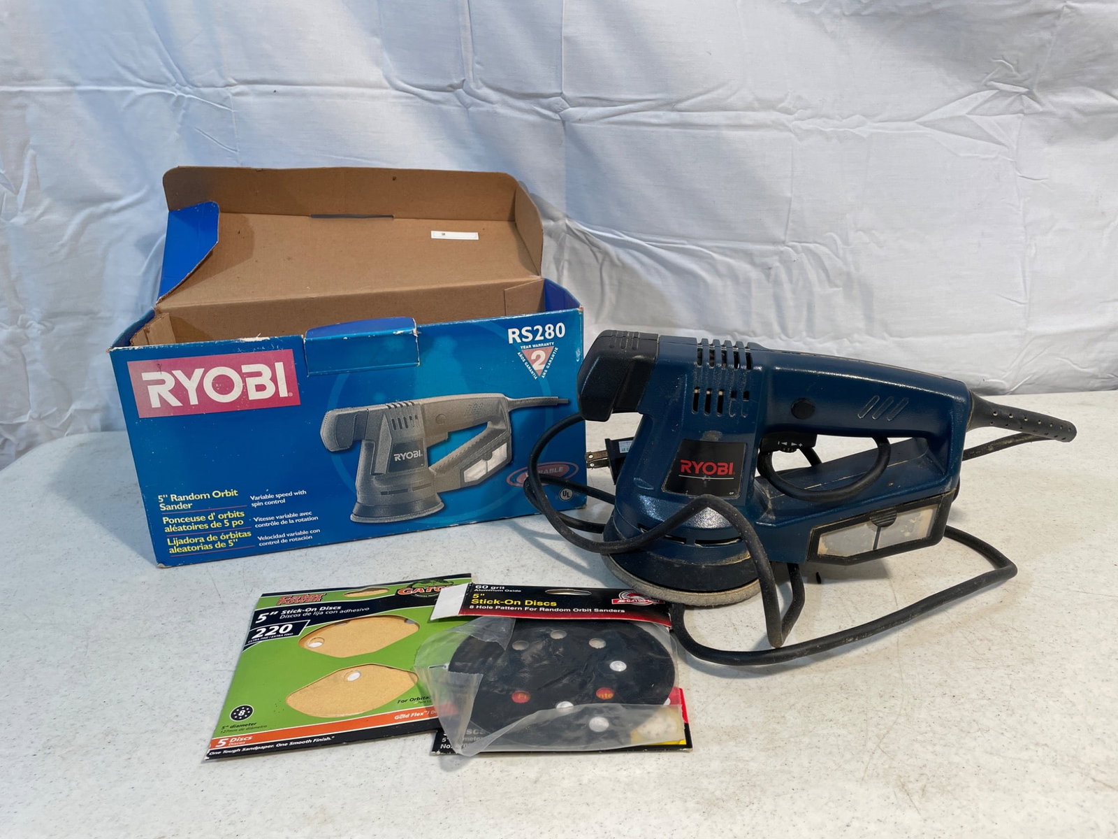 Ryobi RS280 Random Orbit Sander With Accessories: Ryobi RS280 corded random orbit sander, includes original box, sanding discs, and user guide. Designed for wood and other surfaces, 120V input, 280W power, and orbital motion for smooth finishes. Cabl