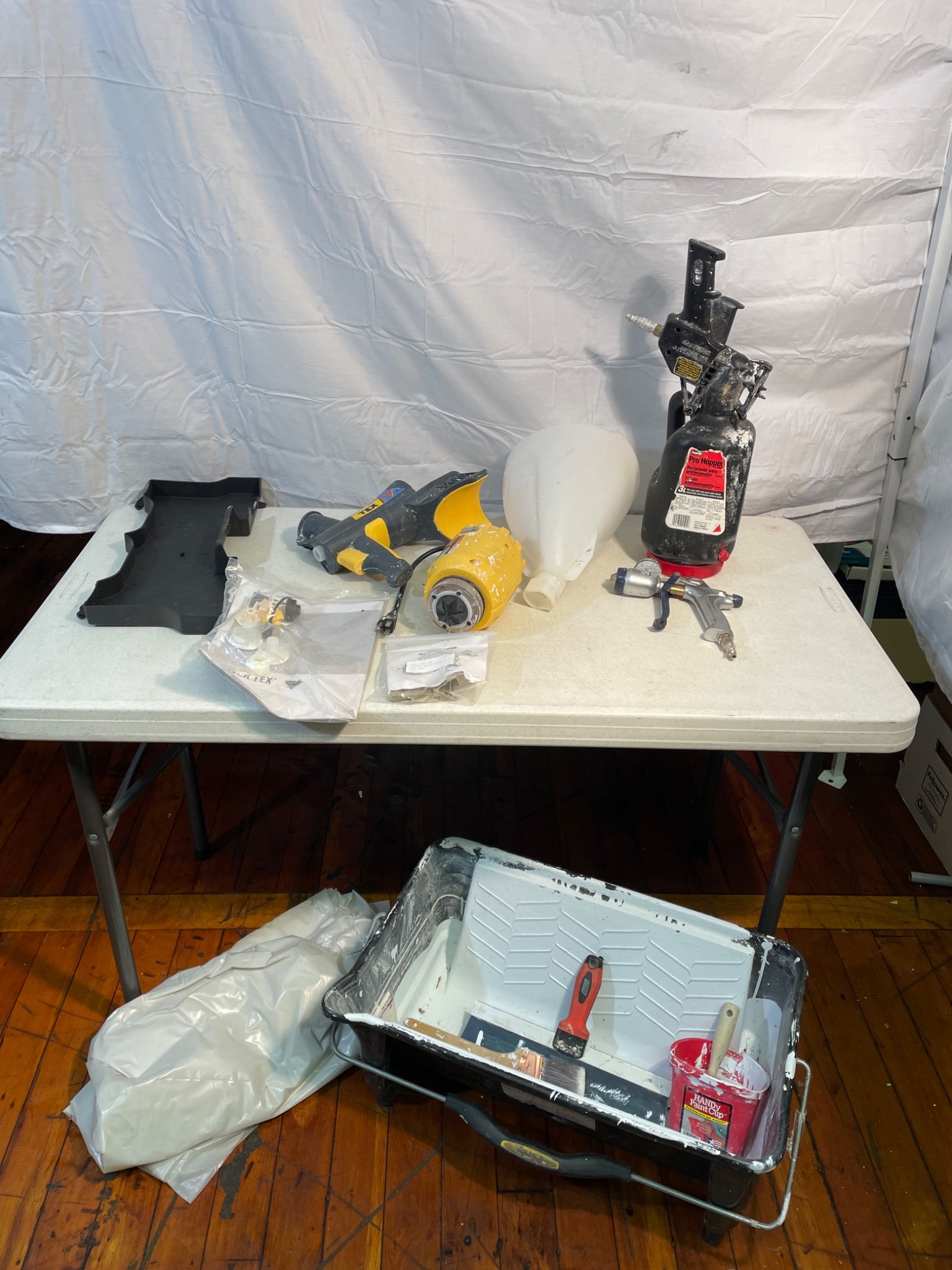 Painting and Texturing Tools Including Wagner Power Tex Sprayer: This lot includes a Wagner Power Tex sprayer, hopper accessories, and spray gun equipment. Additional items include a large paint tray with disposable inserts, brushes, rollers, and a paint mixing buc