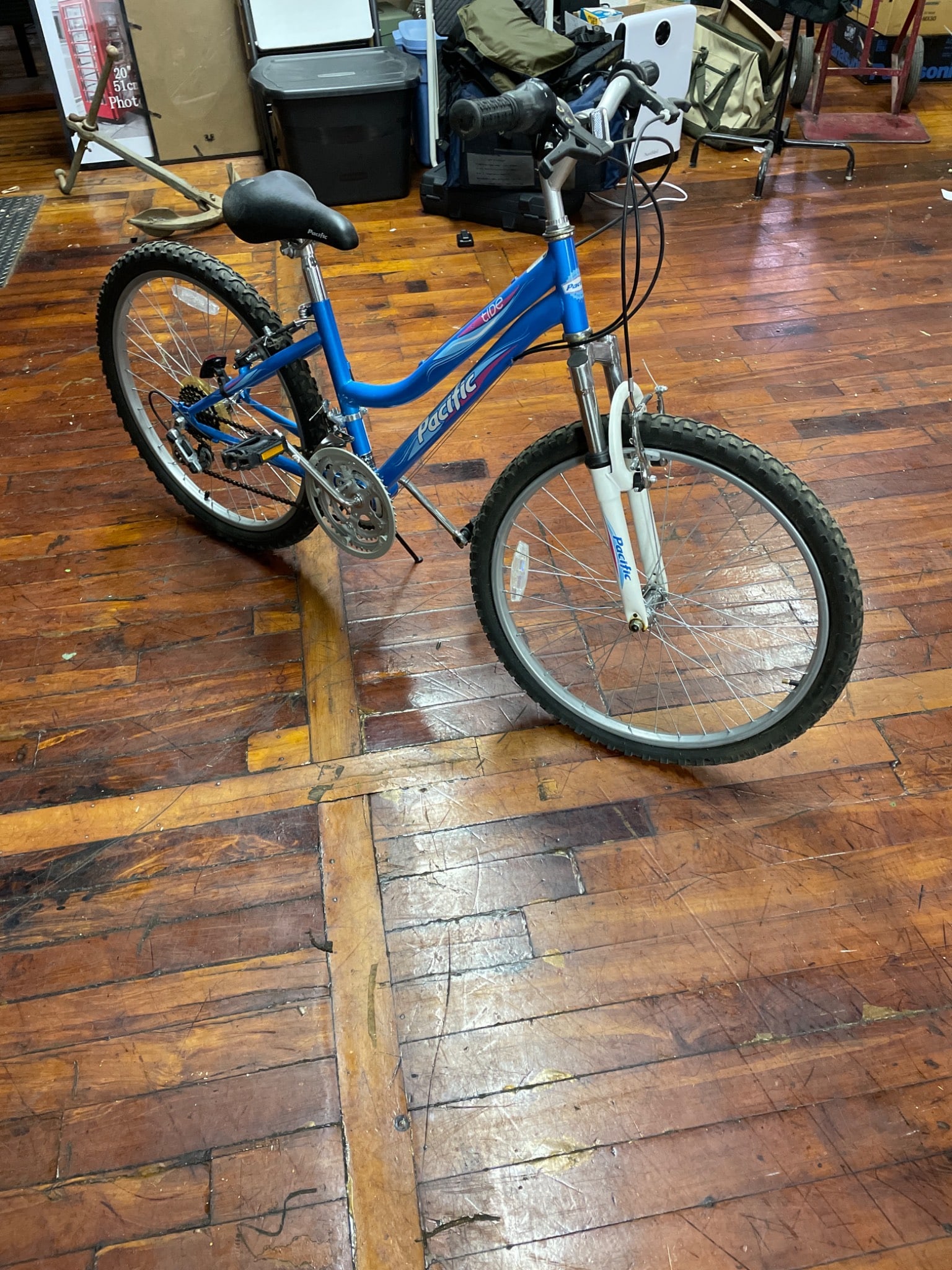 Pacific Tide 18-Speed Mountain Bike, Blue Frame: Pacific Tide 18-speed mountain bike featuring a blue frame with front suspension. The bike requires a new tube for the front tire but appears to be otherwise complete. Includes a Shimano gear system. 