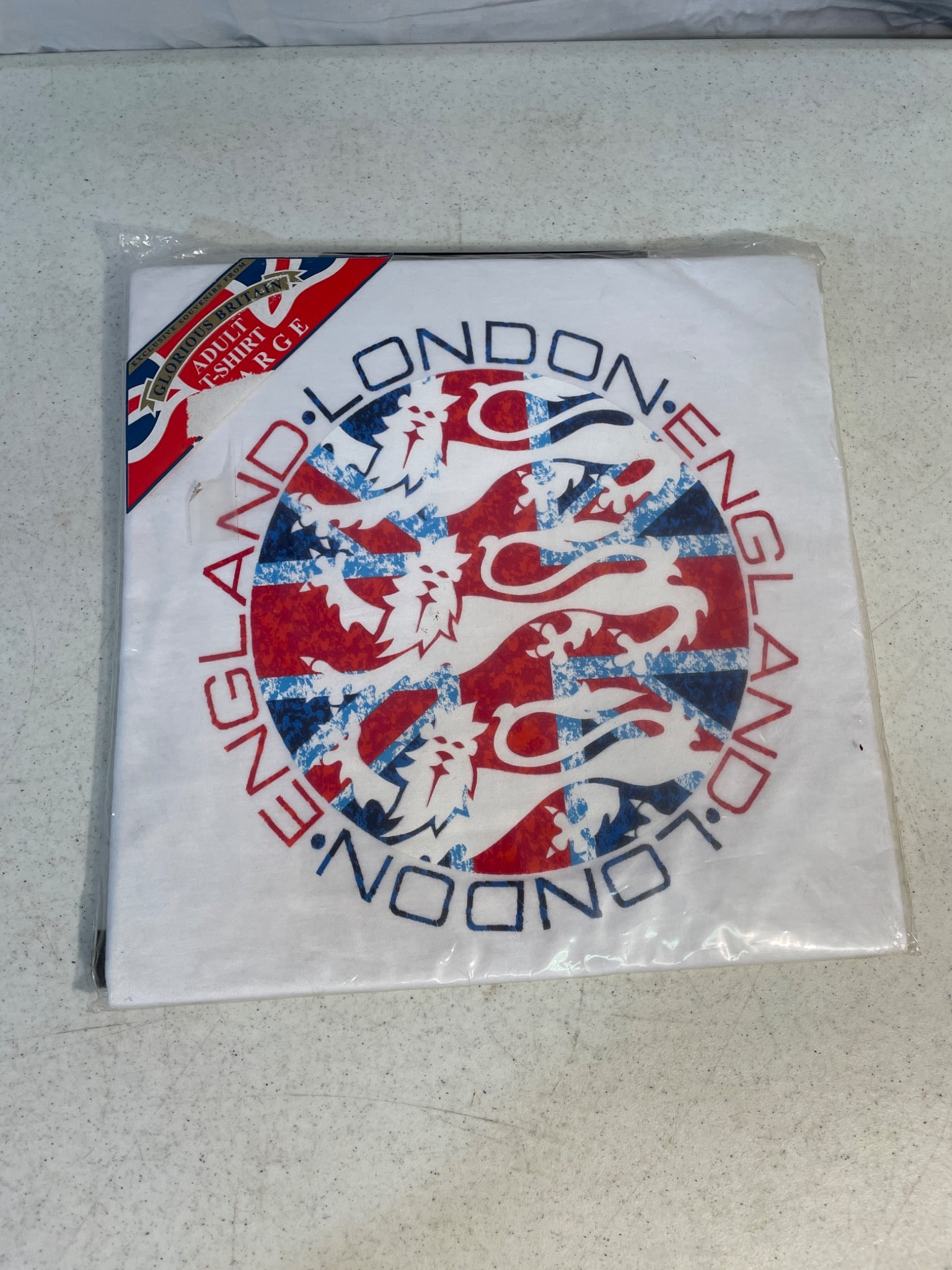 Adult Large England London Graphic T-Shirt in Original Packaging: New adult large T-shirt featuring a graphic design of England and London with a lion emblem and Union Jack motif. The item is still sealed in its original packaging with labels intact. Manufacturer