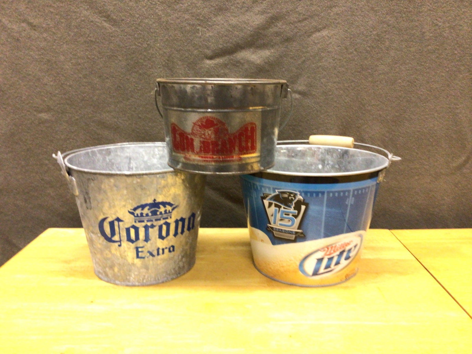 Three Branded Galvanized Metal Beverage Buckets: Three galvanized metal beverage buckets branded with Corona Extra, Red Dog Beer, and Miller Lite 15th Anniversary graphics. The buckets vary slightly in size, with dimensions averaging 8-10 inches in
