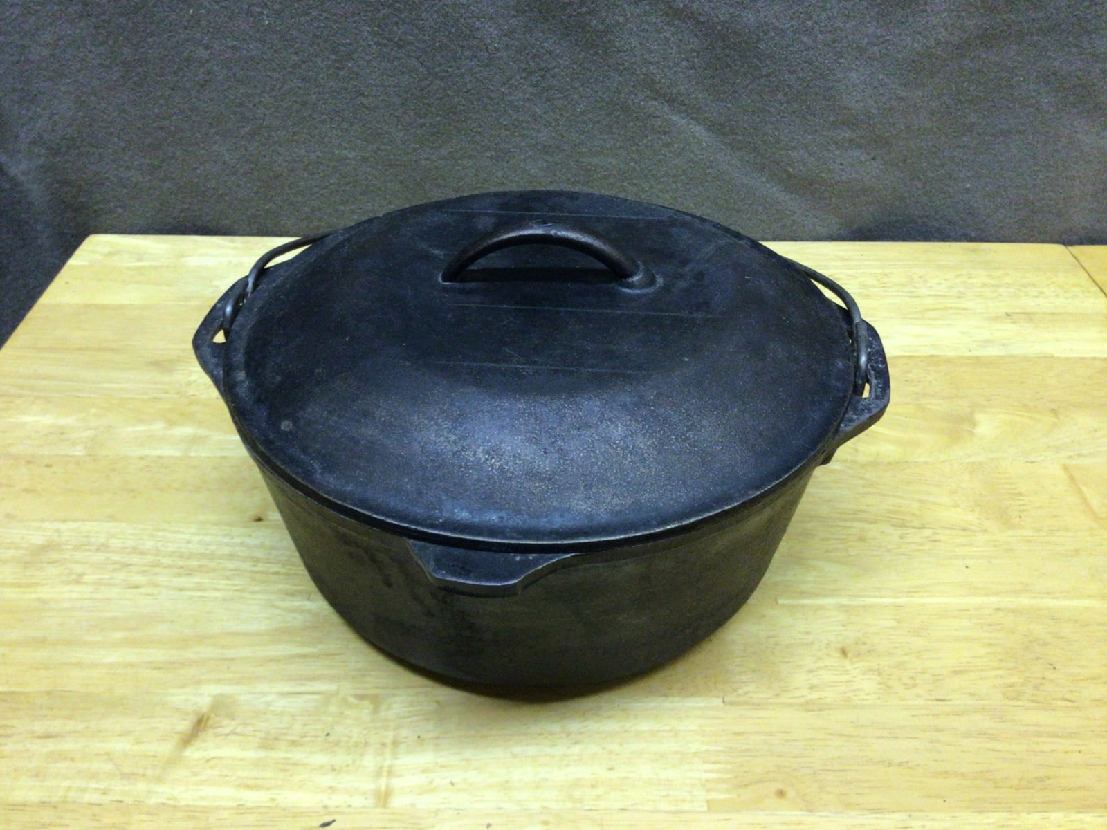 Cast Iron Dutch Oven with Lid and Bail Handle: This is a cast iron Dutch oven with a matching lid featuring a spiked interior design for self-basting. The pot has a bail handle and measures approximately 10 inches in diameter. It does not have