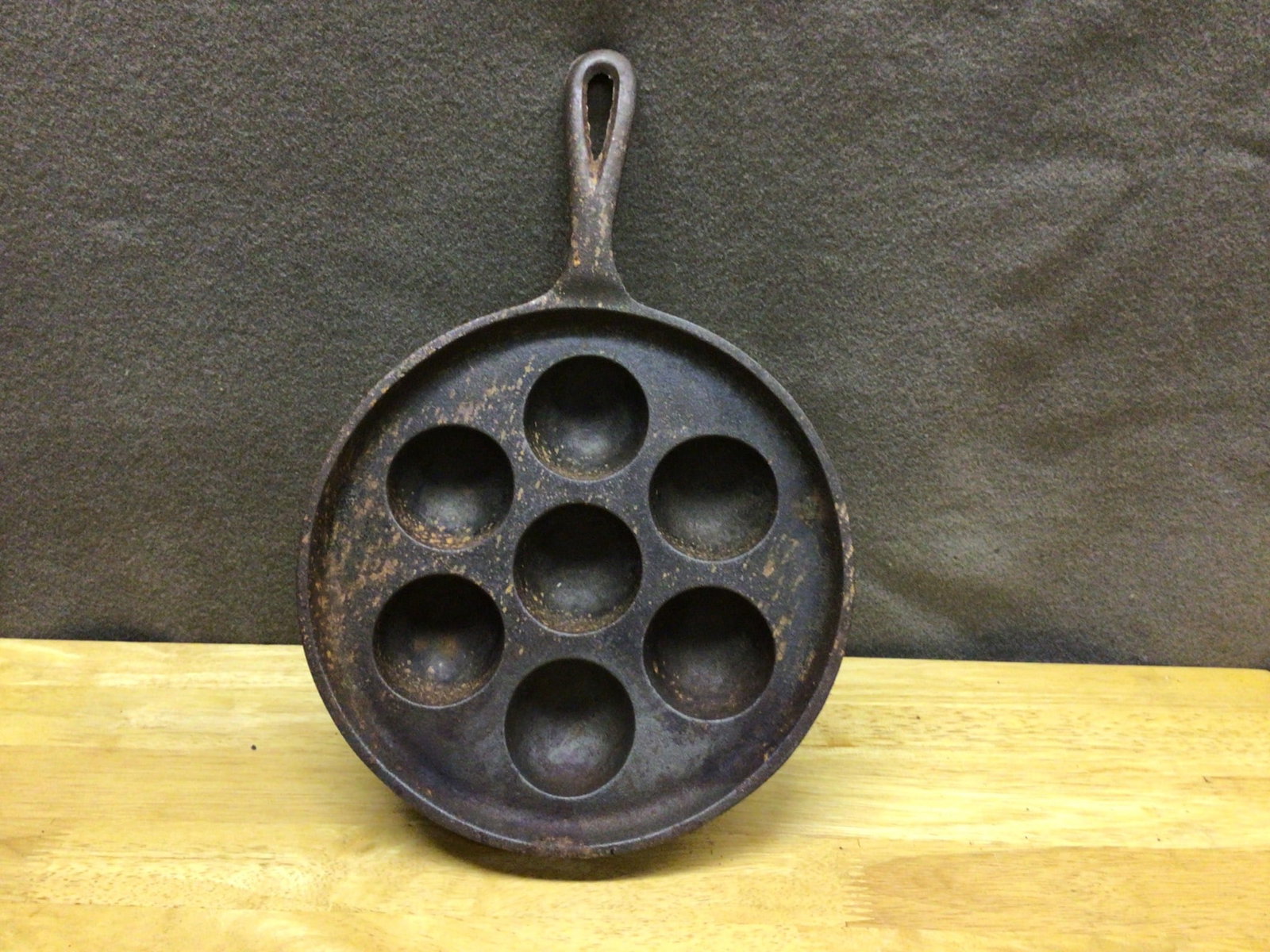 Cast Iron Aebleskiver Pan with Seven Compartments: This cast iron Aebleskiver pan features seven round compartments ideal for creating Danish spherical pancakes. Measuring approximately 8 inches in diameter (not including the handle), this pan has a