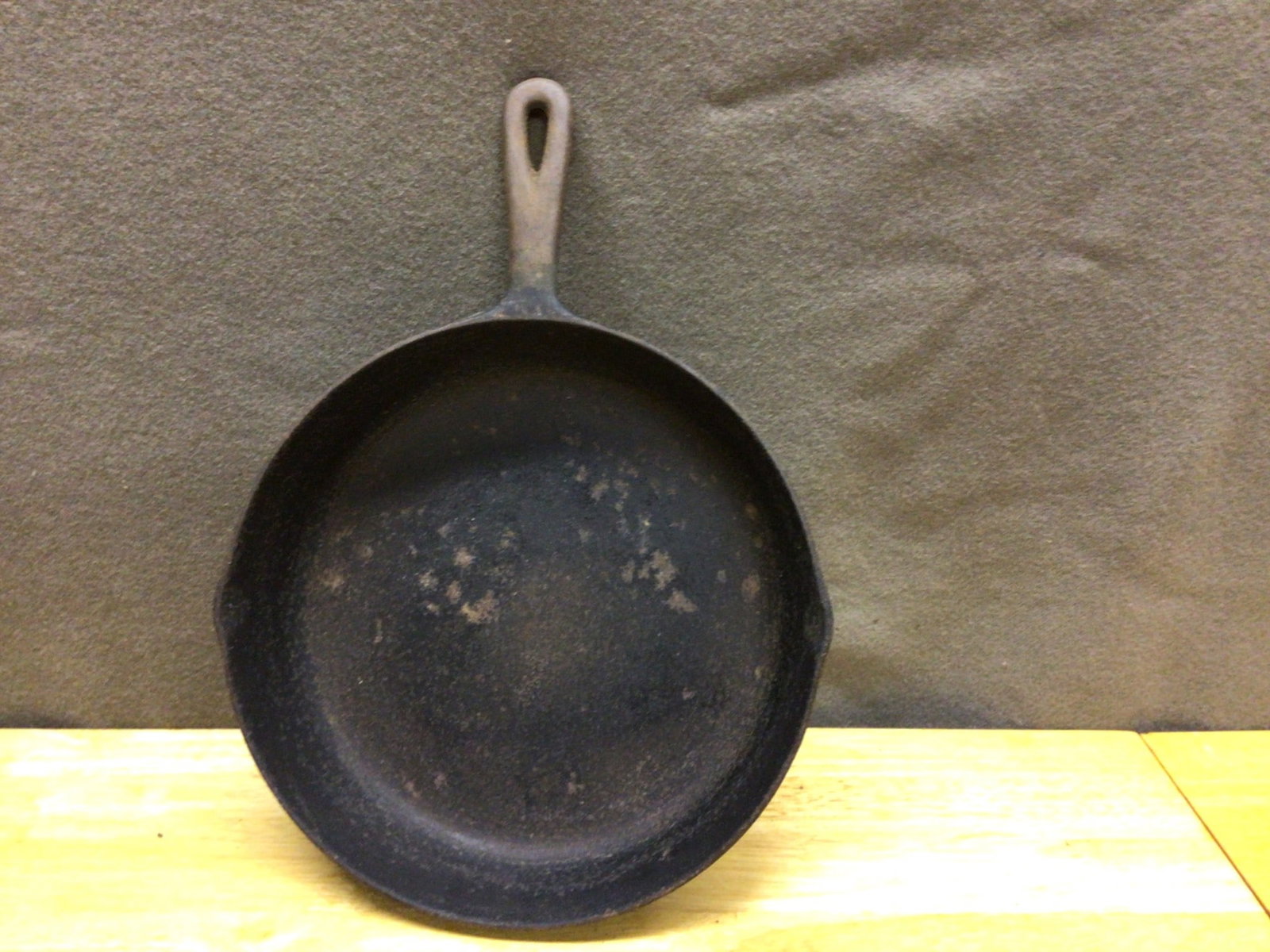 Cast Iron Skillet With Loop Handle, Approximately 12-Inch Diameter: A cast iron skillet featuring a loop handle and a pouring spout on each side. The skillet measures approximately 12 inches in diameter, as indicated in the provided images. This item shows visible