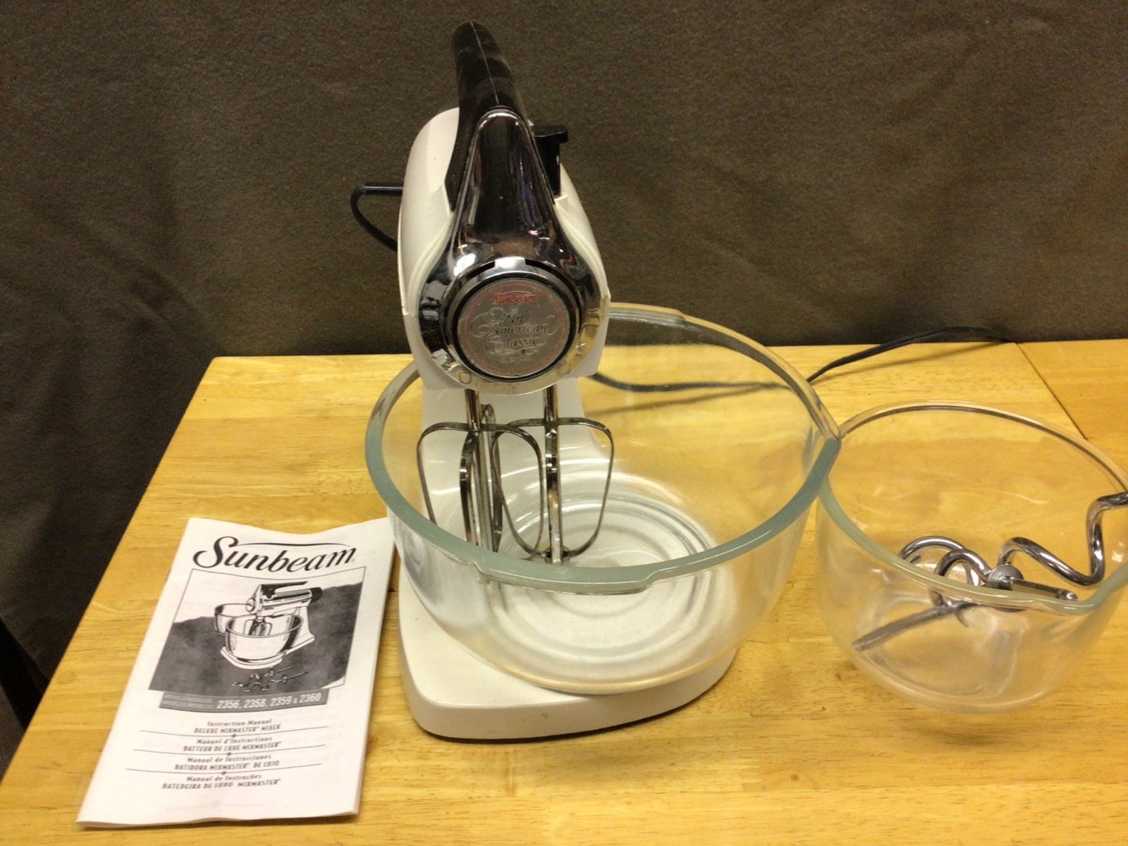 Sunbeam Mixmaster Model 12 Stand Mixer with Accessories: The listing is for a Sunbeam Mixmaster Model 12 stand mixer, featuring its original glass mixing bowls and beaters. The unit includes the instruction manual. The machine is powered via a standard