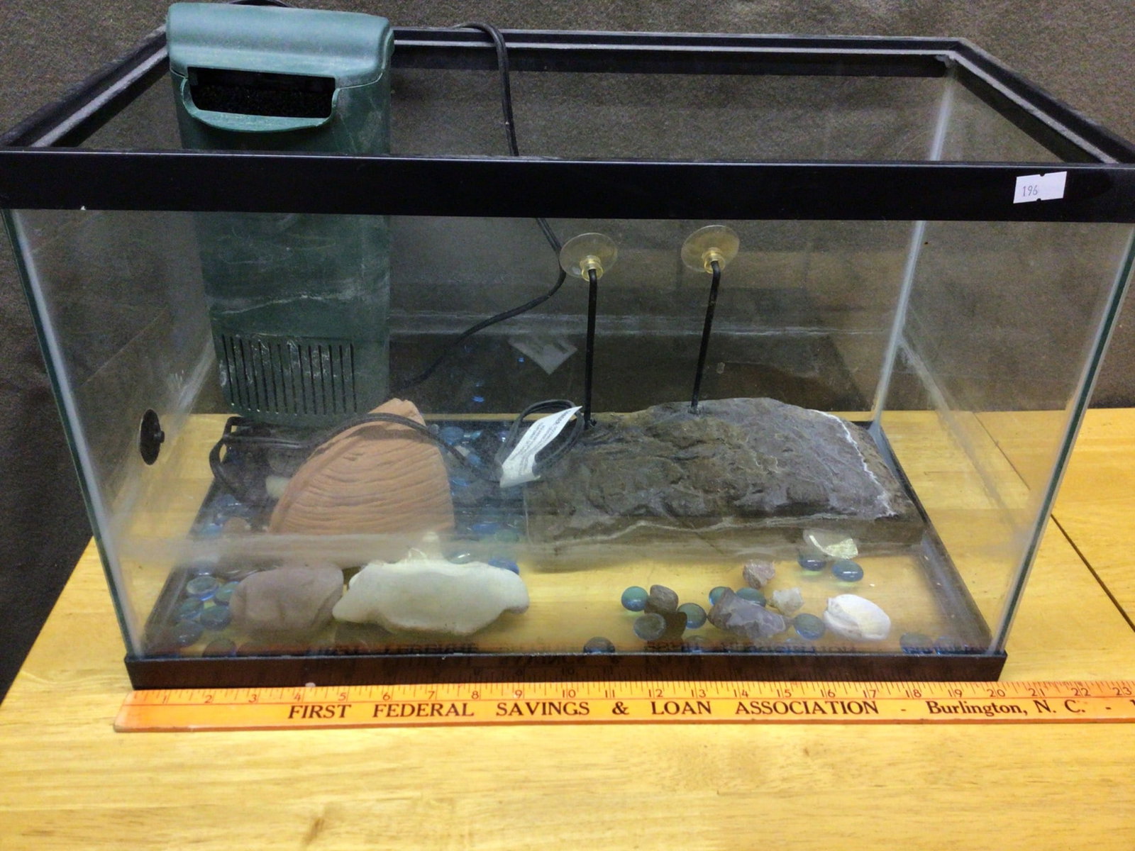 Glass Aquarium With Filter, Stones, and Decorative Accessories: This is a glass aquarium measuring approximately 15 inches in length, accompanied by a fully operational submersible aquarium filter unit. The lot includes decorative elements such as colored stones,