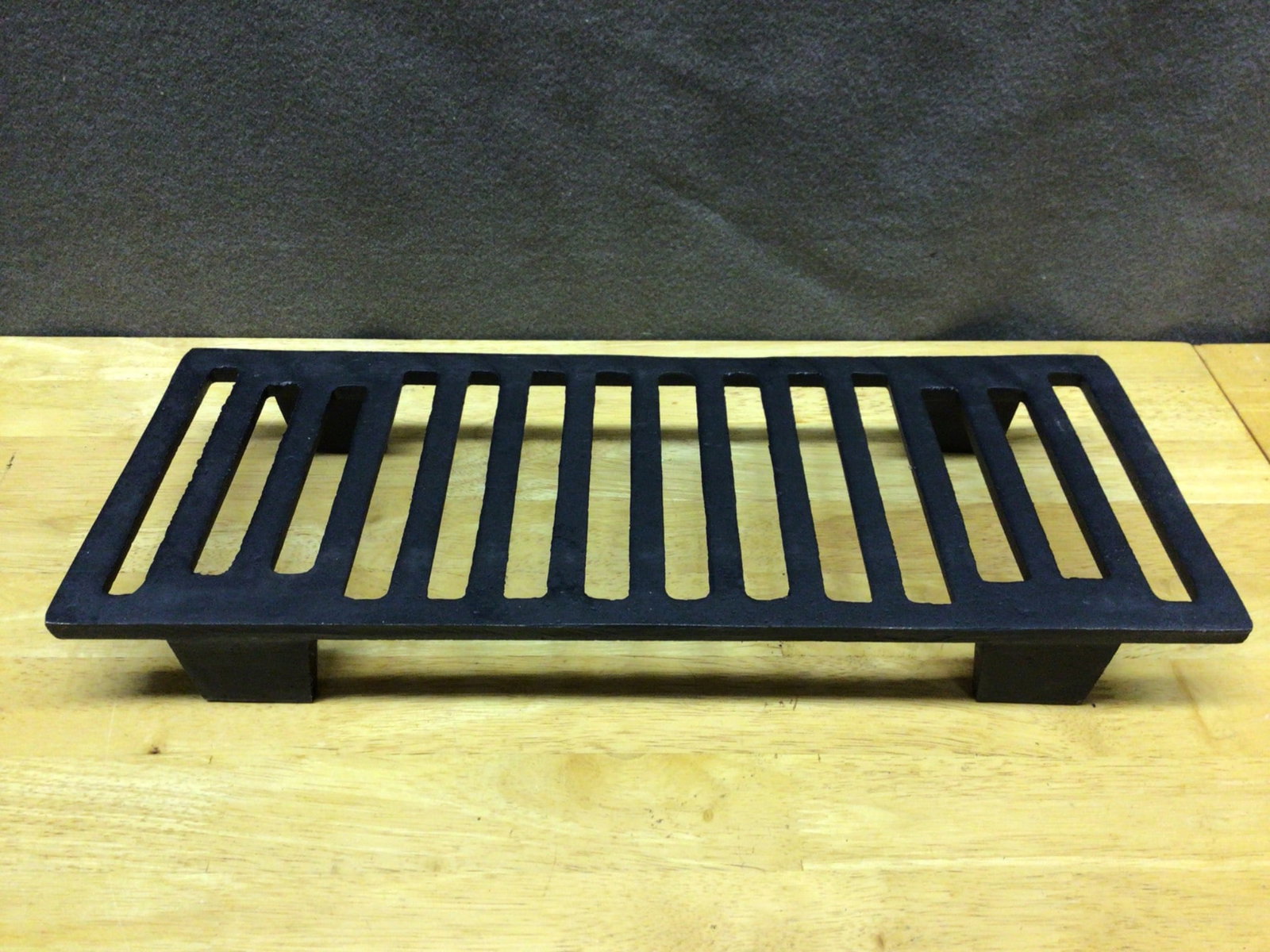 Cast-Iron Grate for Fireplace or Stove with Slotted Design: Rectangular cast-iron grate with a slotted design, measuring approximately 16 inches by 8 inches. Constructed from durable cast-iron material, this grate features legs for elevating off the surface. I