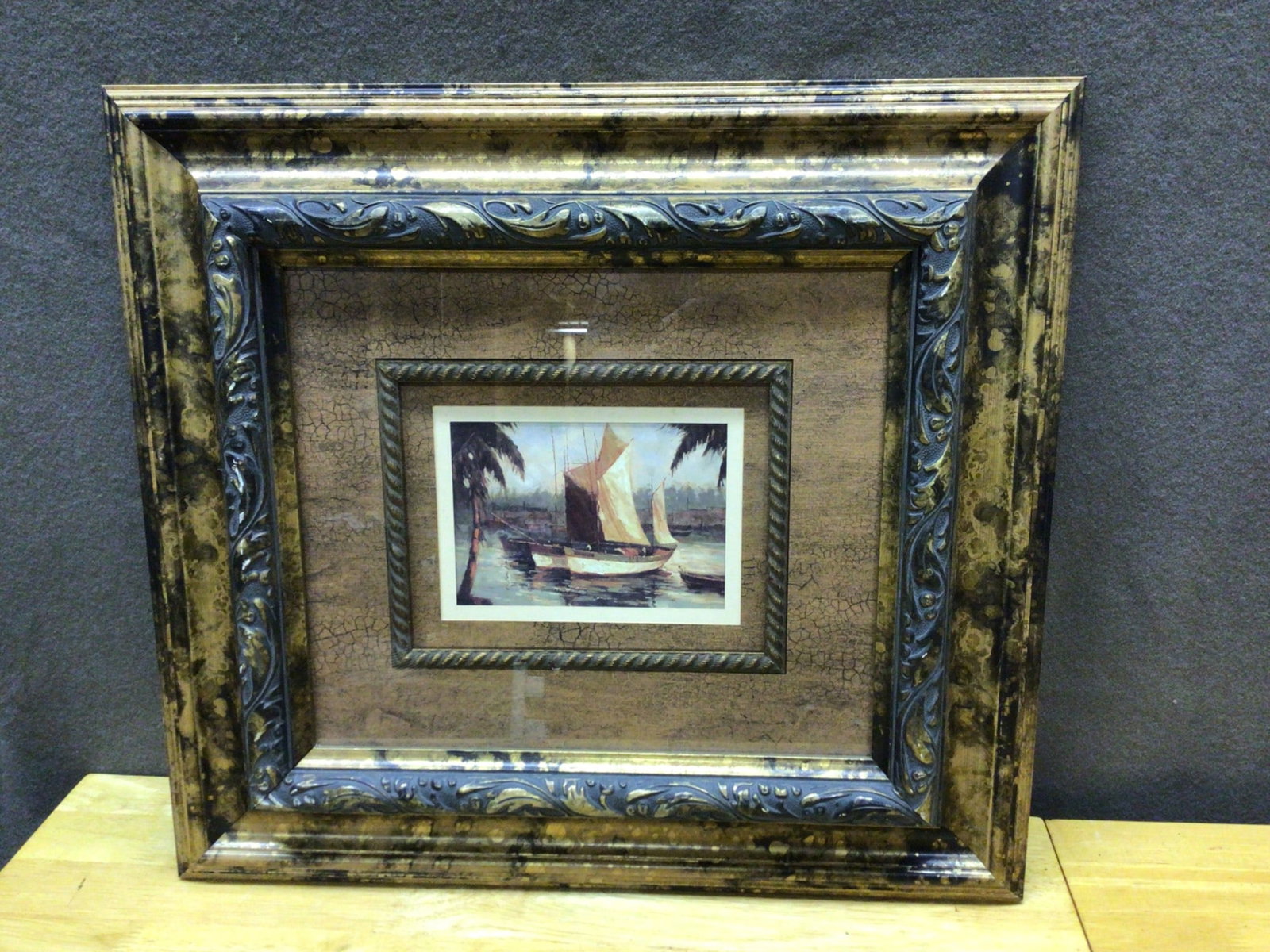 Framed Nautical Print With Decorative Double Layer Frame: This lot includes a framed nautical print depicting a sailboat scene. The artwork features a double-layer decorative frame with ornate detailed molding and a distressed finish. Outer frame dimensions 