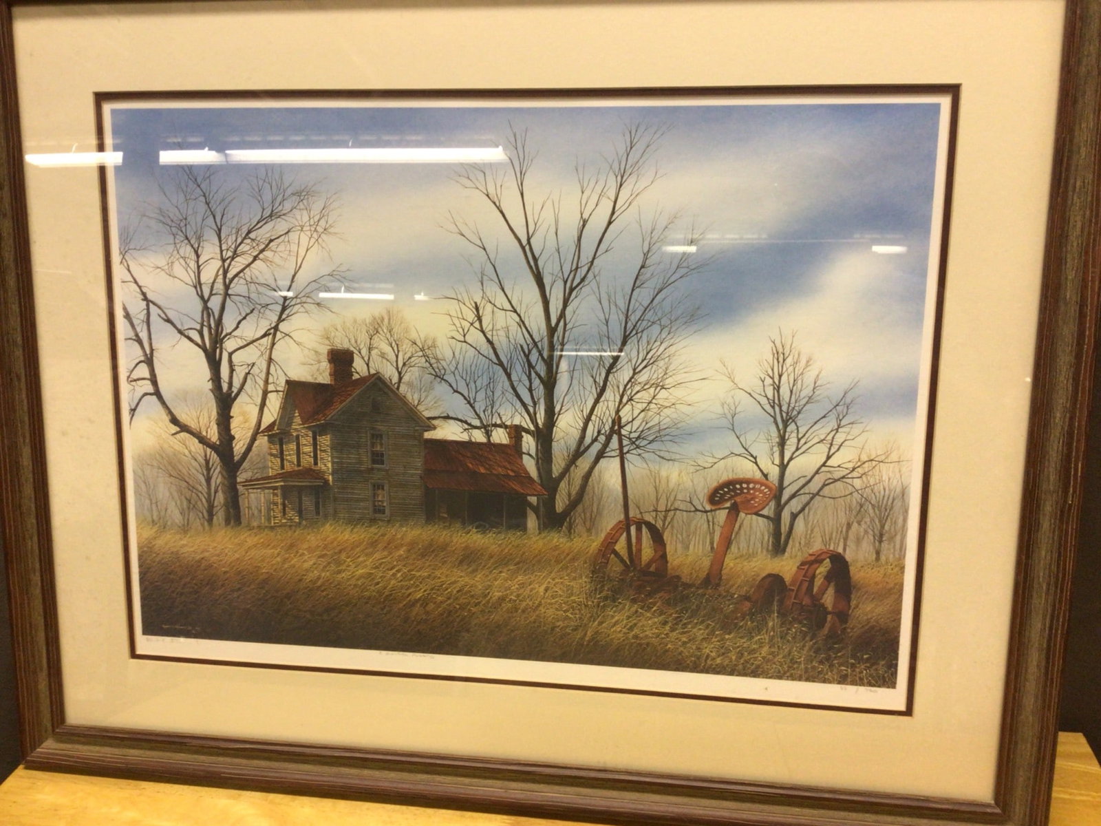 Framed Limited Edition Print Signed and Numbered by Artist: Framed limited edition print depicting a rural landscape with a house and agricultural equipment. Signed by the artist in the lower right and numbered 90/750. The frame measures approximately 28 in. w