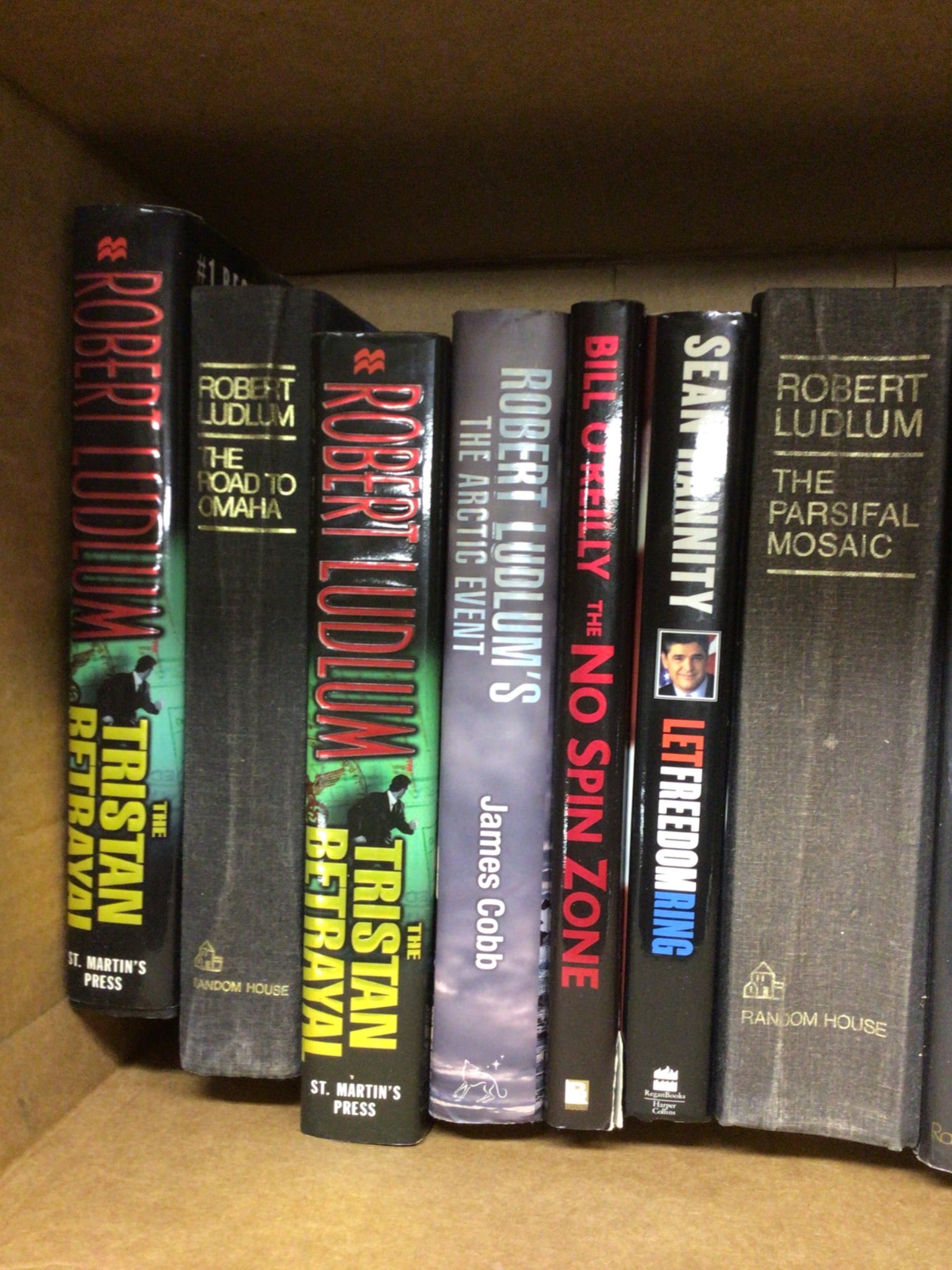 Hardcover Thriller Novels by Robert Ludlum, Bill O'Reilly, and More: This lot includes hardcover books featuring works by Robert Ludlum, Bill O'Reilly, Sean Hannity, and David Poyer. Titles include 'The Tristan Betrayal', 'The Arctic Event', 'The Parsifal Mosaic', 'The