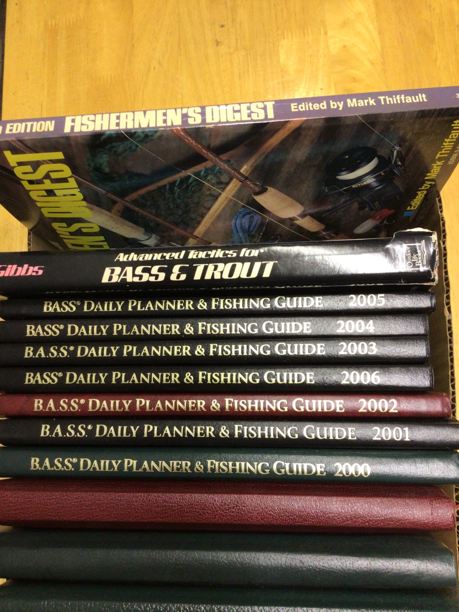 13 Fishing Guides and Planners, Various Years and Editions: This lot includes a set of 13 fishing-related guides and planners, including 'Fishermen's Digest' edited by Mark Thiffault and 'Advanced Tactics for Bass & Trout.' The collection features multiple