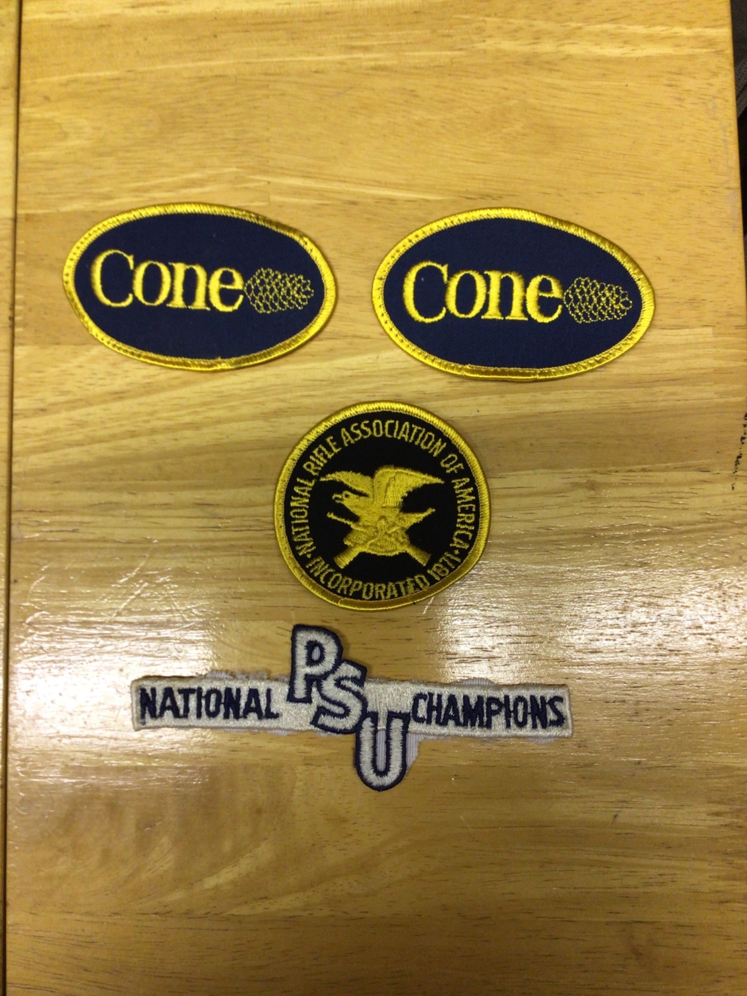 Old Patches Featuring Cone Logos, NRA, and PSU National Champions: Four patches including two 'Cone' logo patches with yellow and navy designs, a National Rifle Association of America patch with an eagle emblem and gold/black color scheme, and a 'PSU National Champio