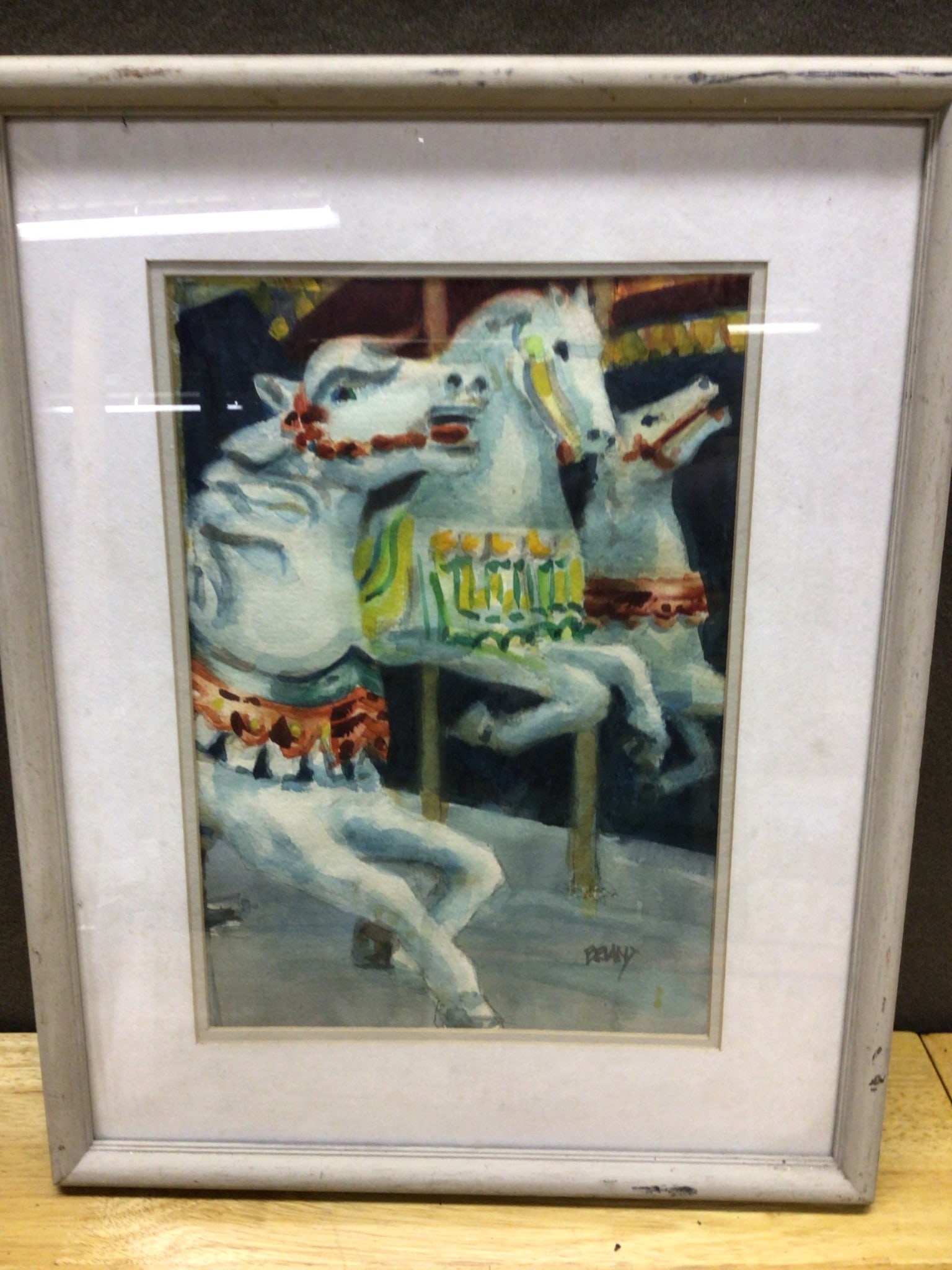 Framed Watercolor Painting Featuring Carousel Horses With Artist Signature: Framed watercolor artwork depicting carousel horses in vibrant colors. The piece is signed by the artist, 'Perry,' in the lower right corner. The frame is of a light color with visible wear and