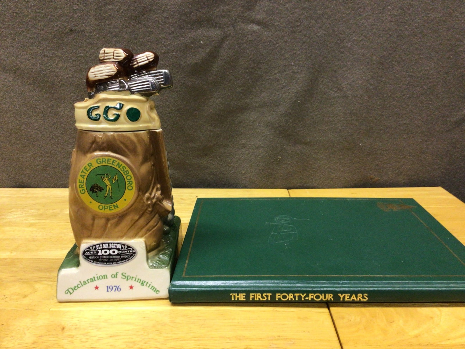 1976 Greater Greensboro Open Stein and Book Set: This lot includes a commemorative ceramic stein from the 1976 Greater Greensboro Open (GGO) golf tournament and a book titled 'The First Forty-Four Years,' detailing the history of the GGO. The stein