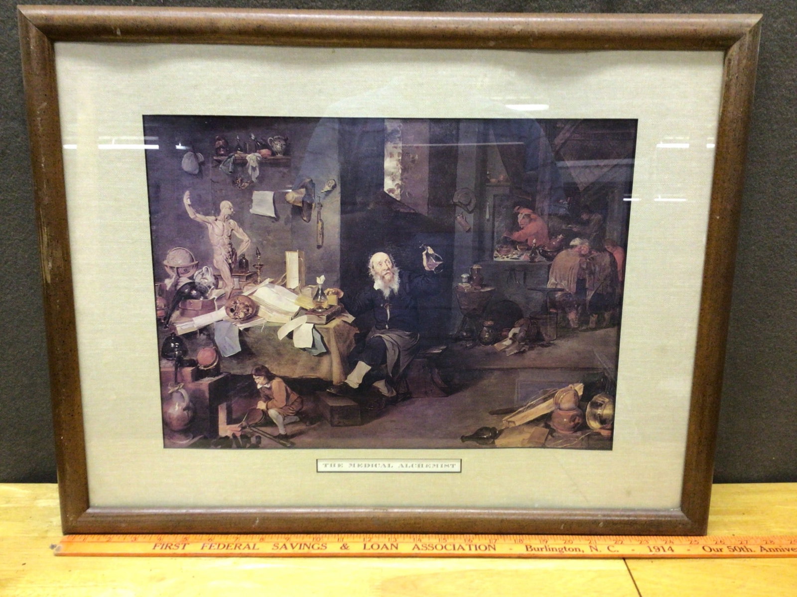 Framed Print of 'The Medical Alchemist' with Wooden Frame: This is a framed print titled 'The Medical Alchemist.' The frame measures approximately 20 x 16 inches and includes a wooden frame with glass covering. The piece has a wired backing for wall