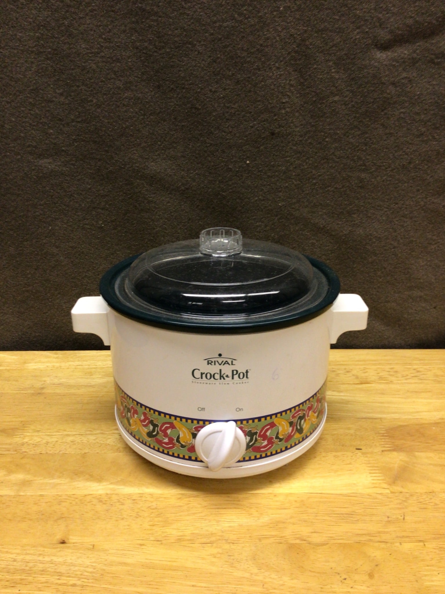 Rival Crock-Pot Slow Cooker Model 3100 With Glass Lid And Floral Detail: This Rival Crock-Pot slow cooker (model 3100) features a removable ceramic inner pot, glass lid, and floral pattern detailing on the exterior. It includes an adjustable control knob for temperature