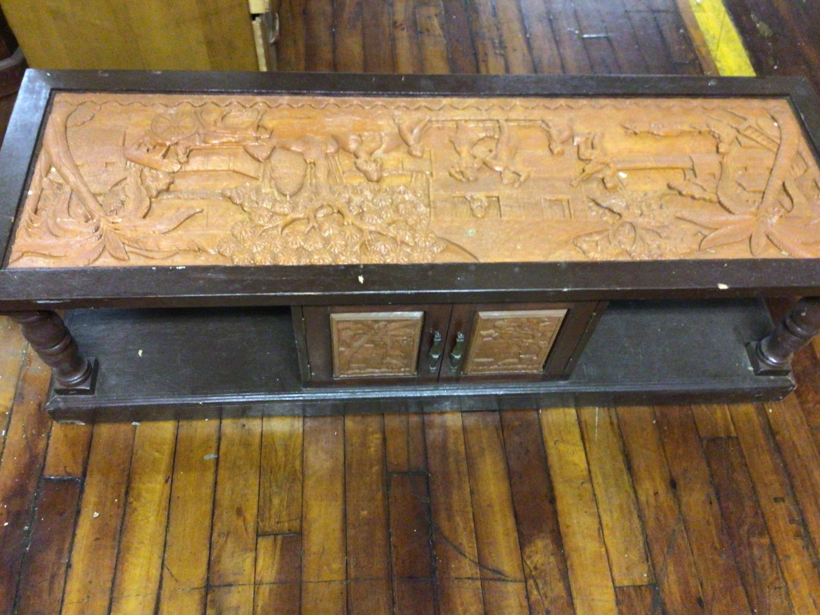 Wooden Coffee Table With Carved Relief Panel and Storage Cabinet, 60x20x18 Inches: This coffee table measures 60 inches wide, 20 inches deep, and 18 inches tall. The tabletop features an intricately carved relief panel depicting a rural scene with people, animals, and natural