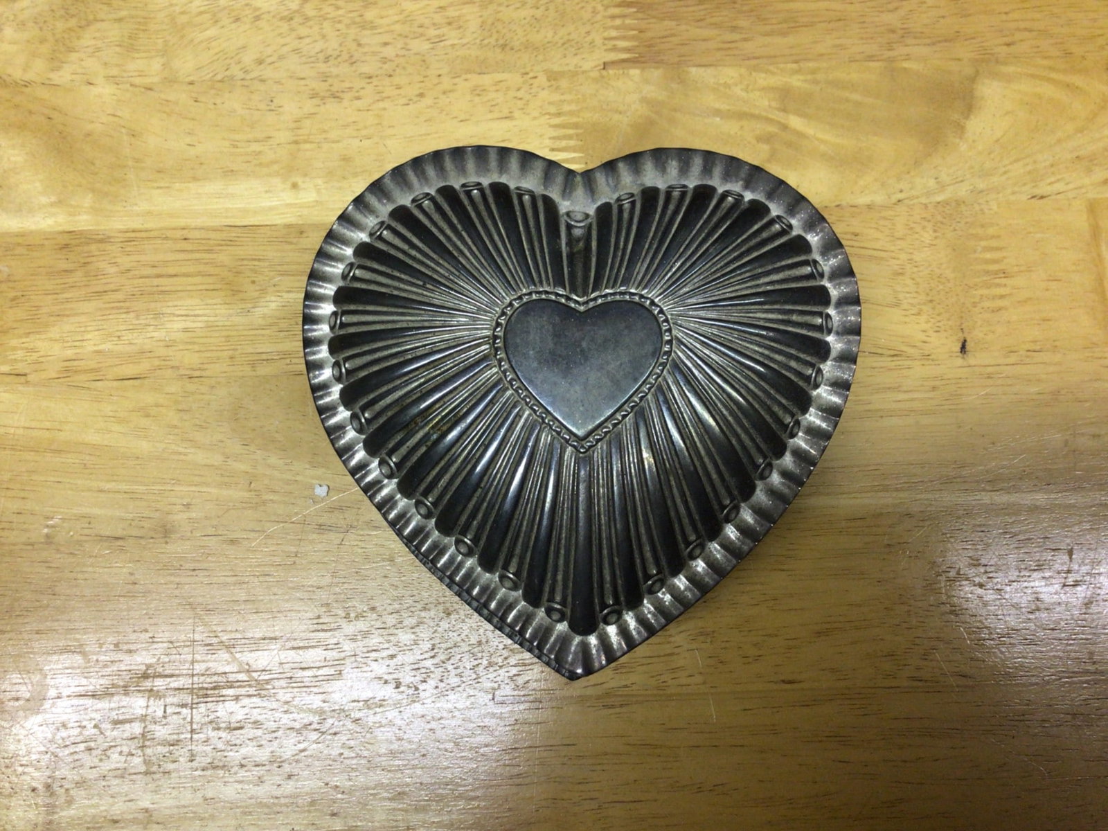 Heart-Shaped Metal Box With Red Felt Interior: Heart-shaped metal box featuring a cut-out heart design on the lid. The interior and bottom are lined with red felt. The box measures approximately 5 inches across at its widest point. Condition