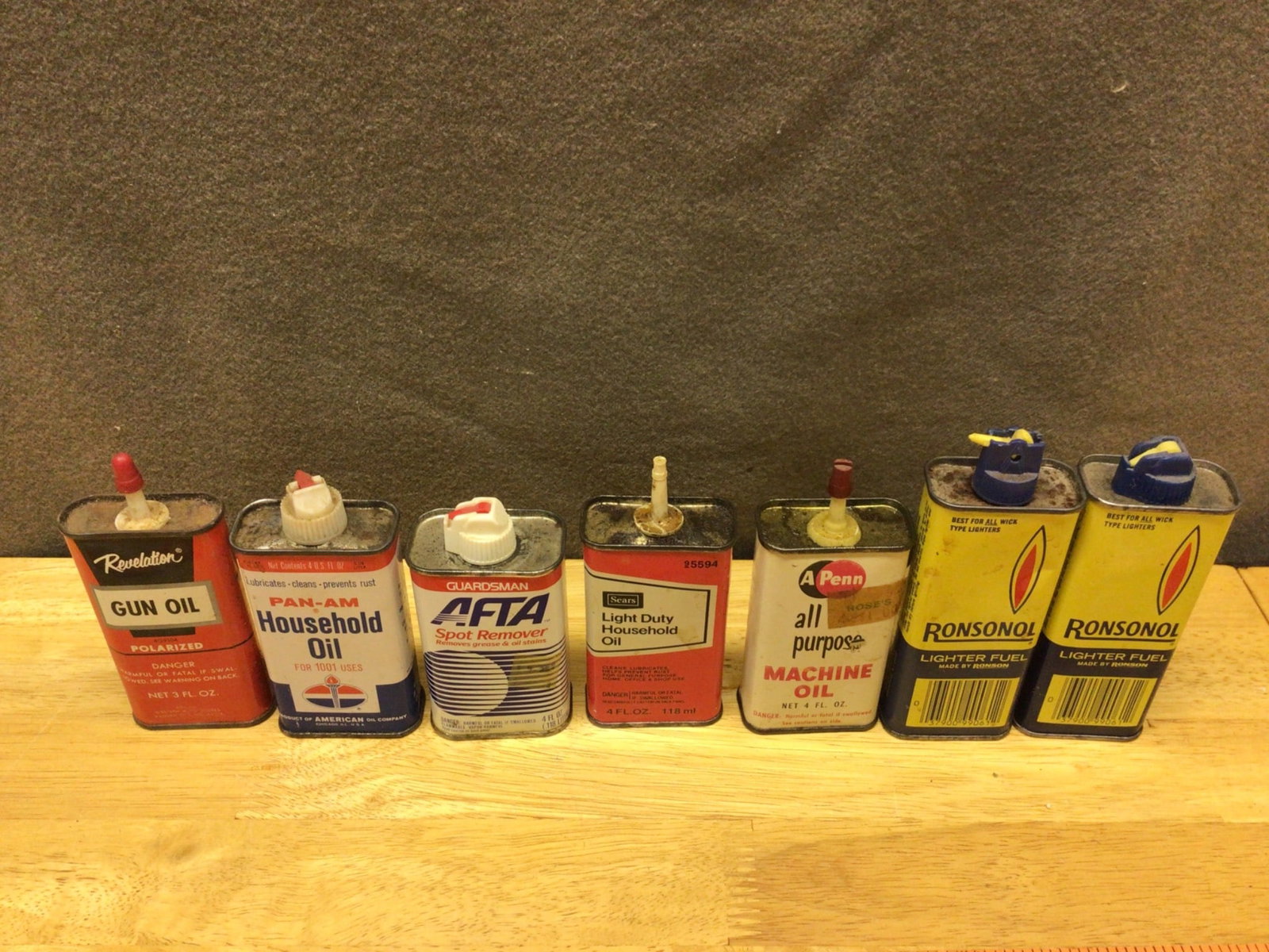 Seven Vintage Oil and Fluid Tins Including Brands Such as Ronsonol and Pan-Am: This lot includes seven tins of various household and specialty oils. Brands featured include Ronsonol Lighter Fluid, Pan-Am Household Oil, Guardsman Stain Remover, Sears Household Oil, A-Penn All-Pur