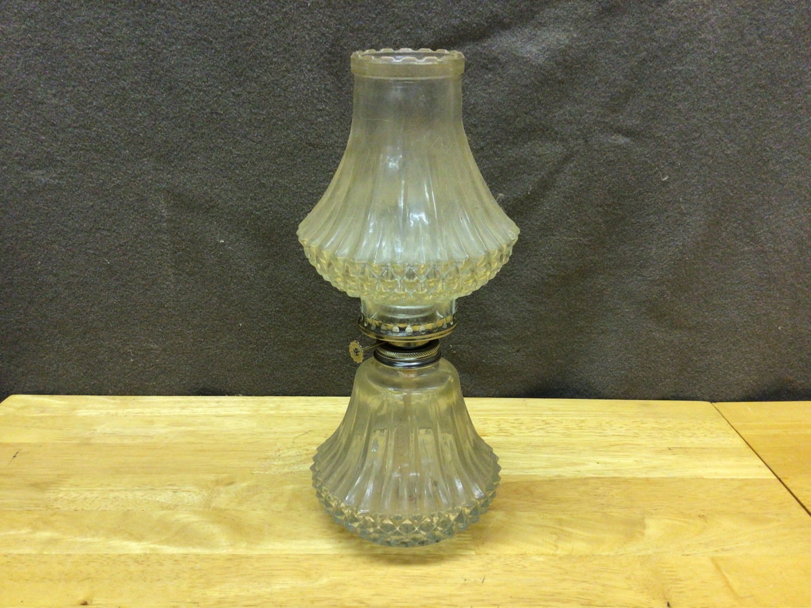 Glass Oil Lamp With Ribbed and Diamond Pattern Details: This is a glass oil lamp featuring a ribbed and diamond pattern on its base and shade. The item measures approximately 10 inches in height. The metal burner assembly appears intact, and the wick