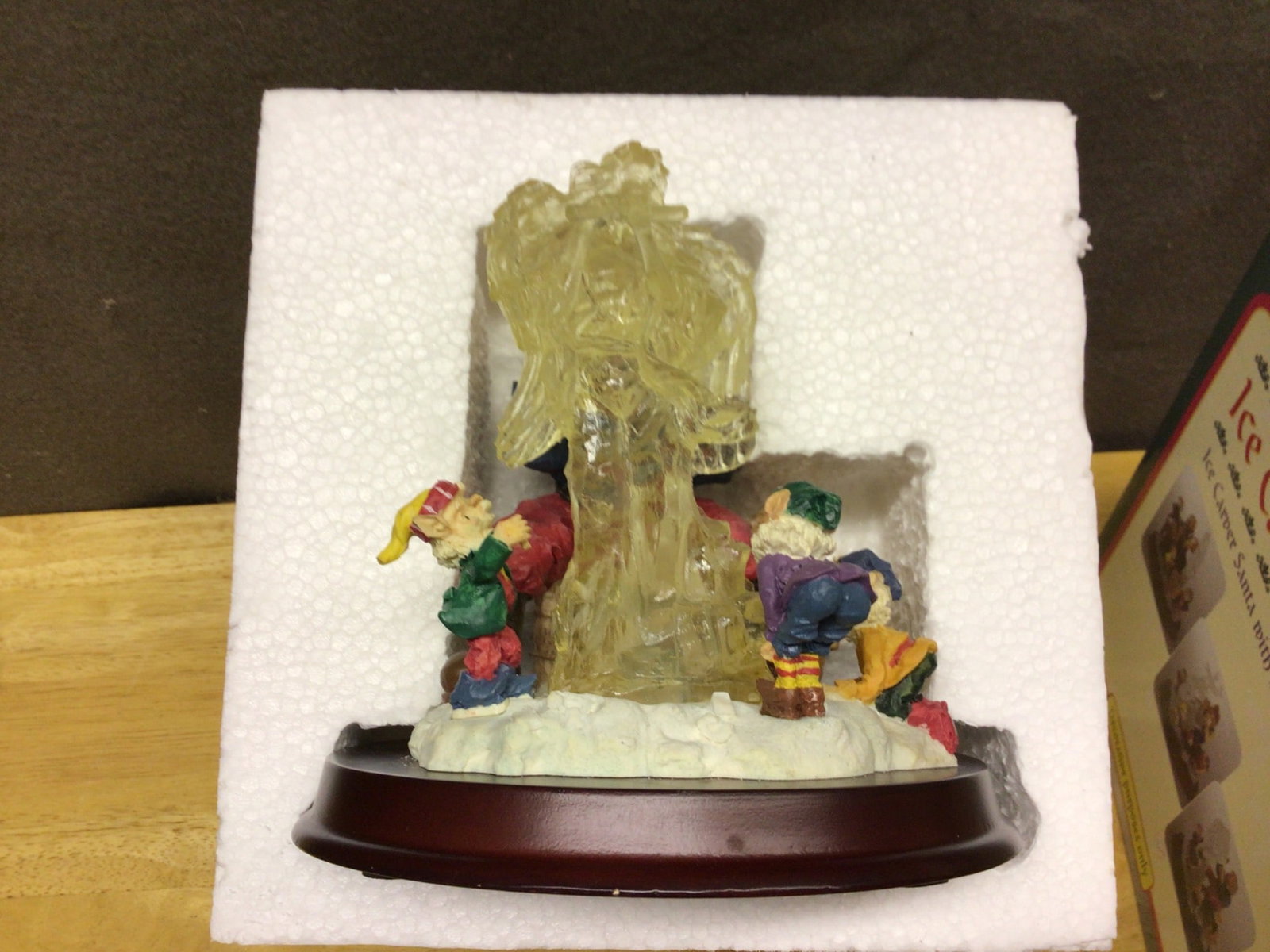 Ice Carver Santa Decorative Figurine With Lights: Ice Carver Santa figurine featuring multiple figures sculpting an ice structure. It includes integrated lighting features as described on the packaging. Operates with AA batteries (not included). The