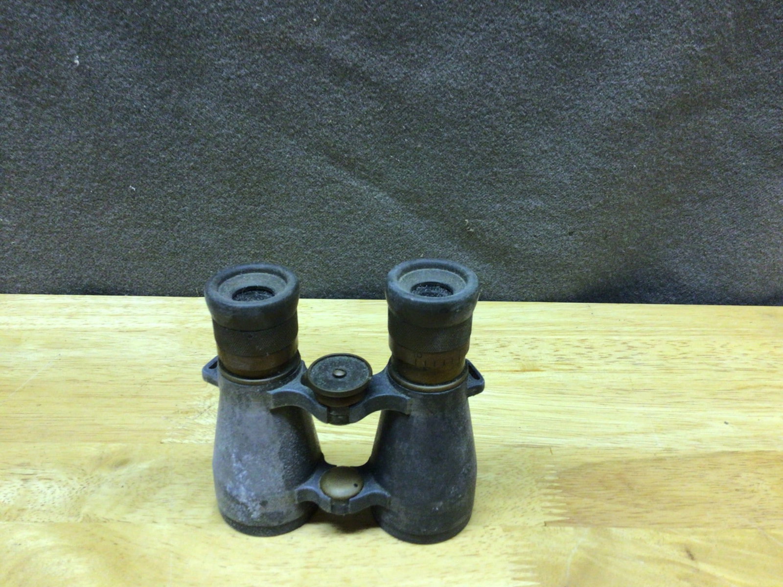 German Metal Binoculars with Central Focus Knob: Old metal binoculars crafted in Germany. Features a central focus knob and two objective lenses with visible wear on the metal body and optics. The manufacturer's branding or model information is