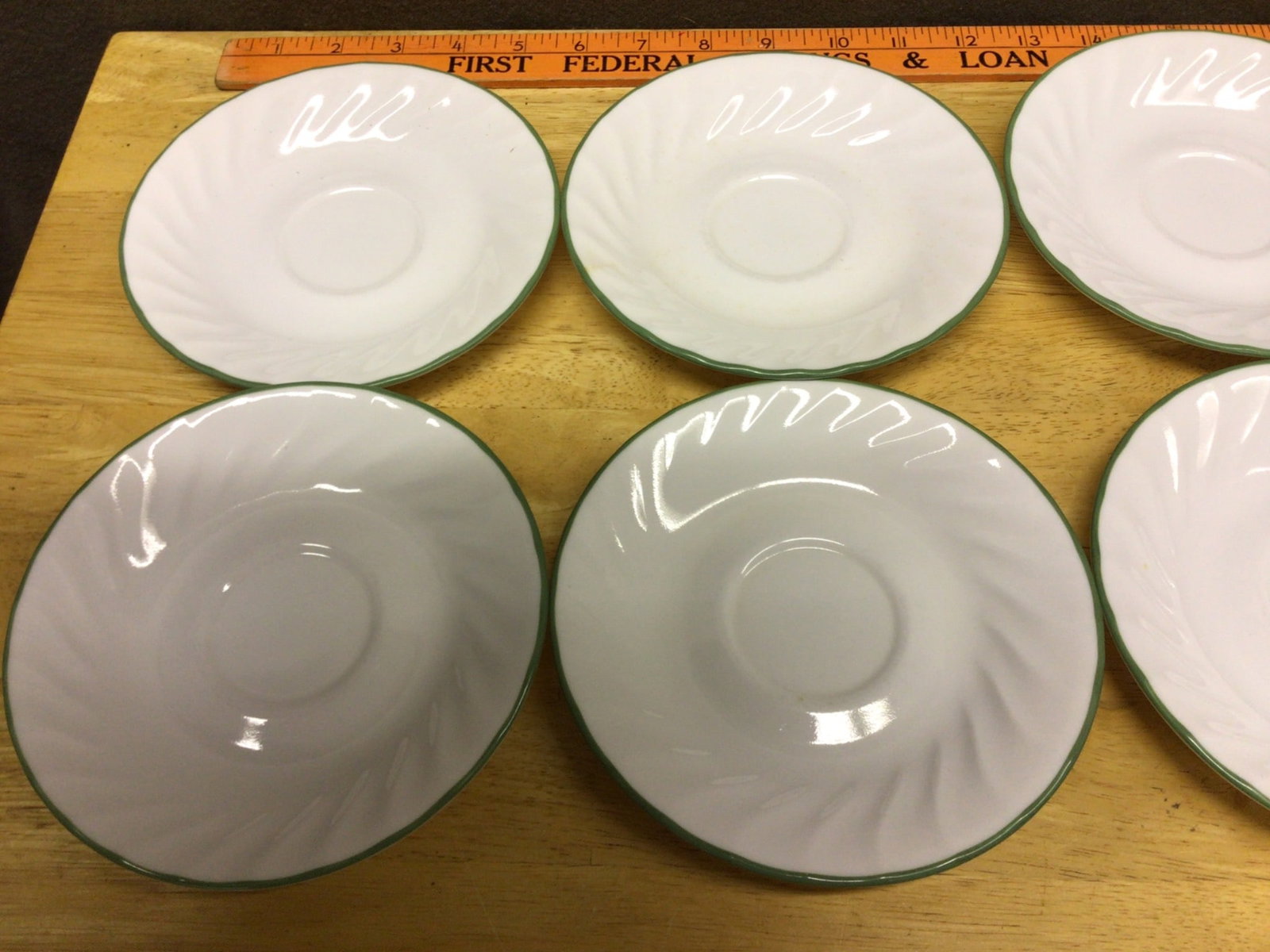 Six Corelle Green-Trimmed White Saucer Plates, Model 103A: This lot includes six Corelle saucer plates, model 103A, featuring a green trim on a white background with a swirl design. They are marked 'Break & Chip Resistant Corelle, Made in USA, No Stovetop or 