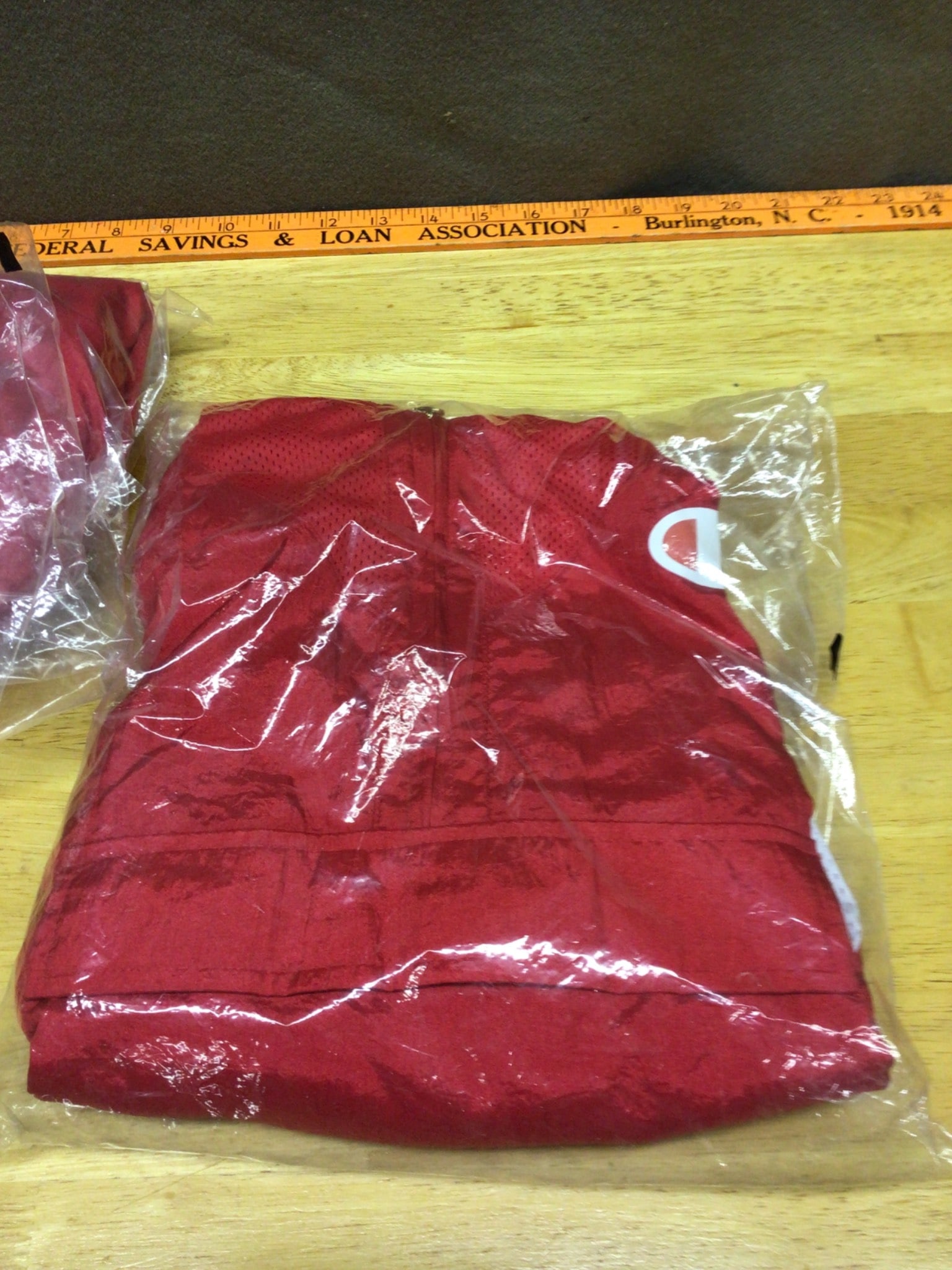 Champion Hoodies and Windbreakers, Medium and Small: This lot includes two Champion windbreaker hoodies: one in medium (model JL947, tag 19280325759) and one in small (model JL947, tag 19280325782). Both items are individually packaged in their