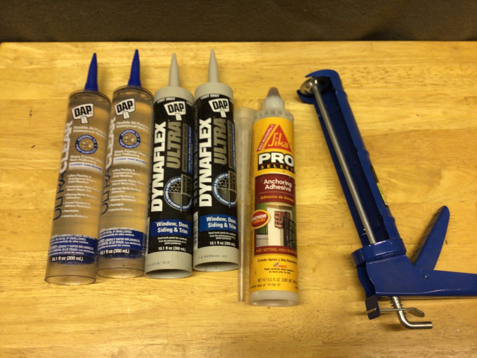 DAP Dynaflex Ultra Sealants, Sika Pro Adhesive & Caulk Gun, Brand New: This lot includes 4 units of DAP Dynaflex Ultra sealants (10.1 fl. oz each, Light Gray color), 1 unit of Sika Pro Select Anchoring Adhesive (10.1 fl. oz), and 1 blue caulking gun. All items are brand